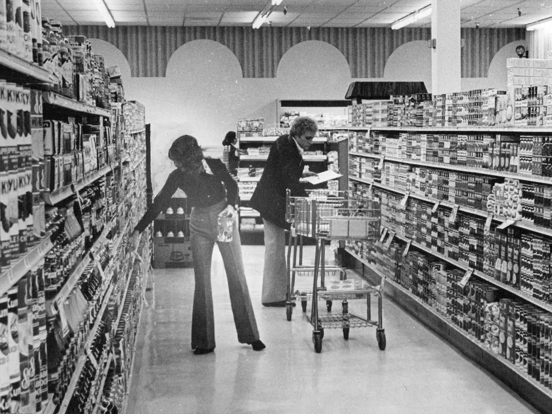 Two people shopping in a grocery store aisle in 1975.