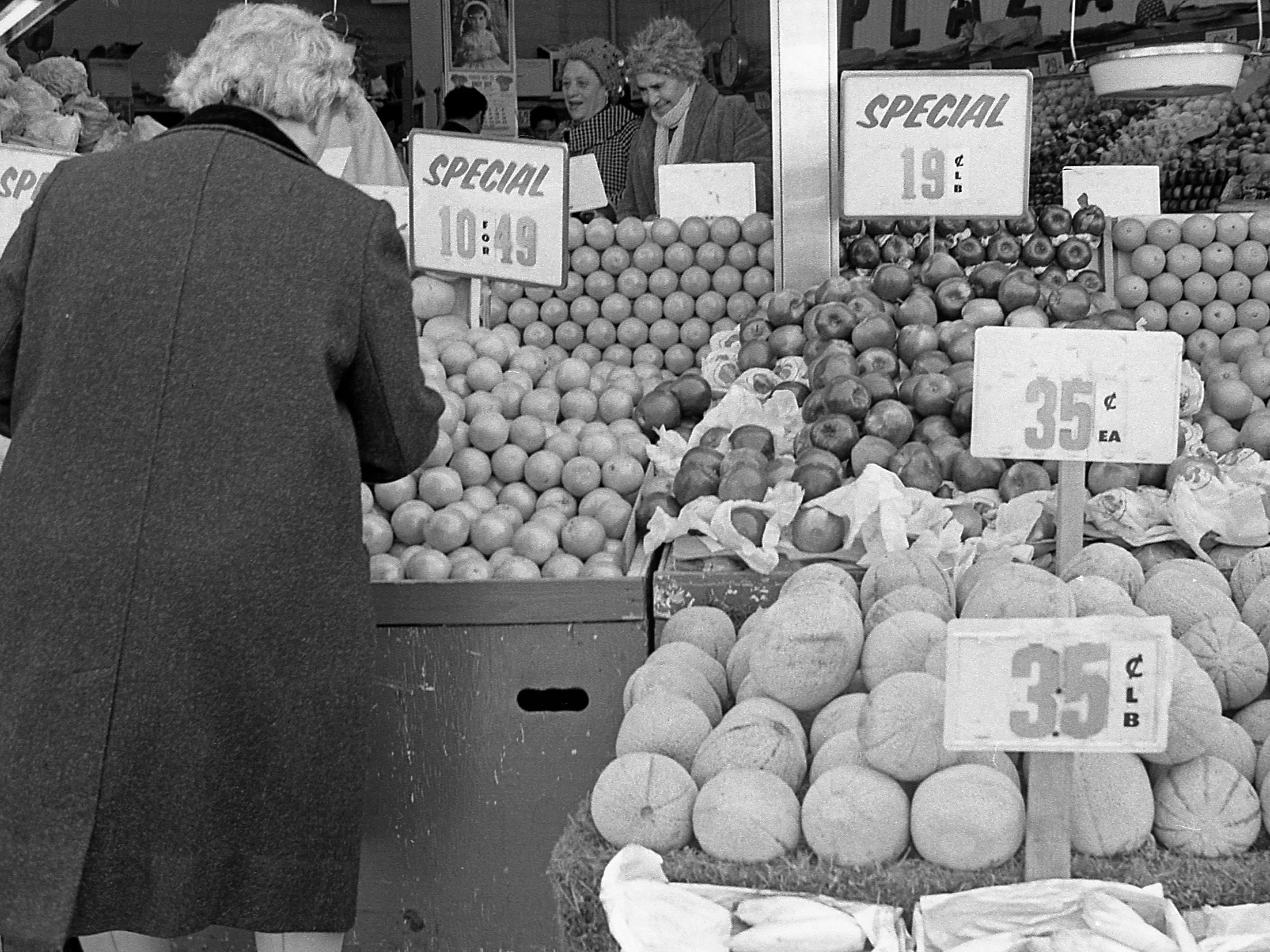 A person shopping at an outdoor produce market in New York City, circa 1970.