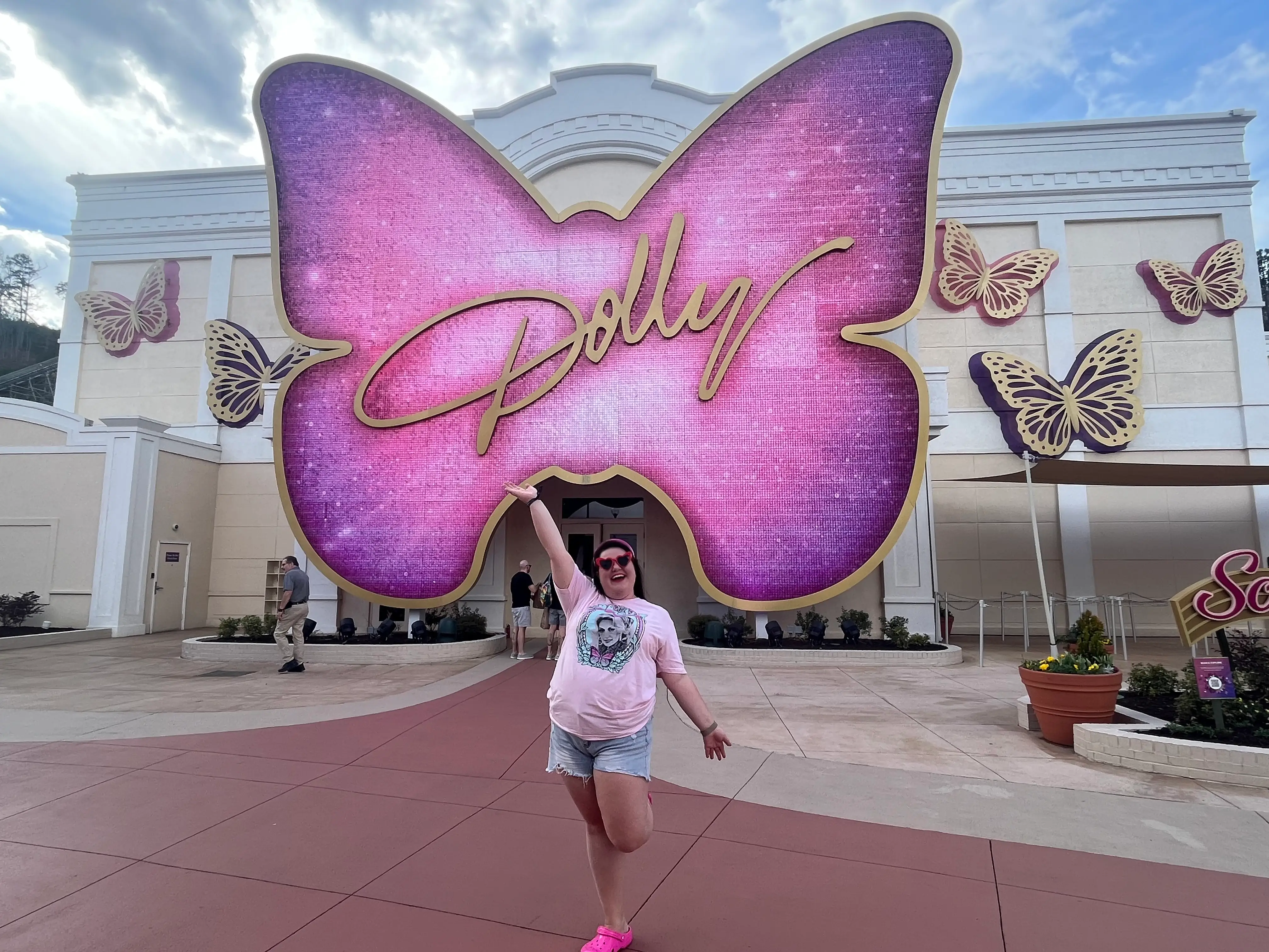 Megan duBois posing in front of a giant pink butterfly sign that says 