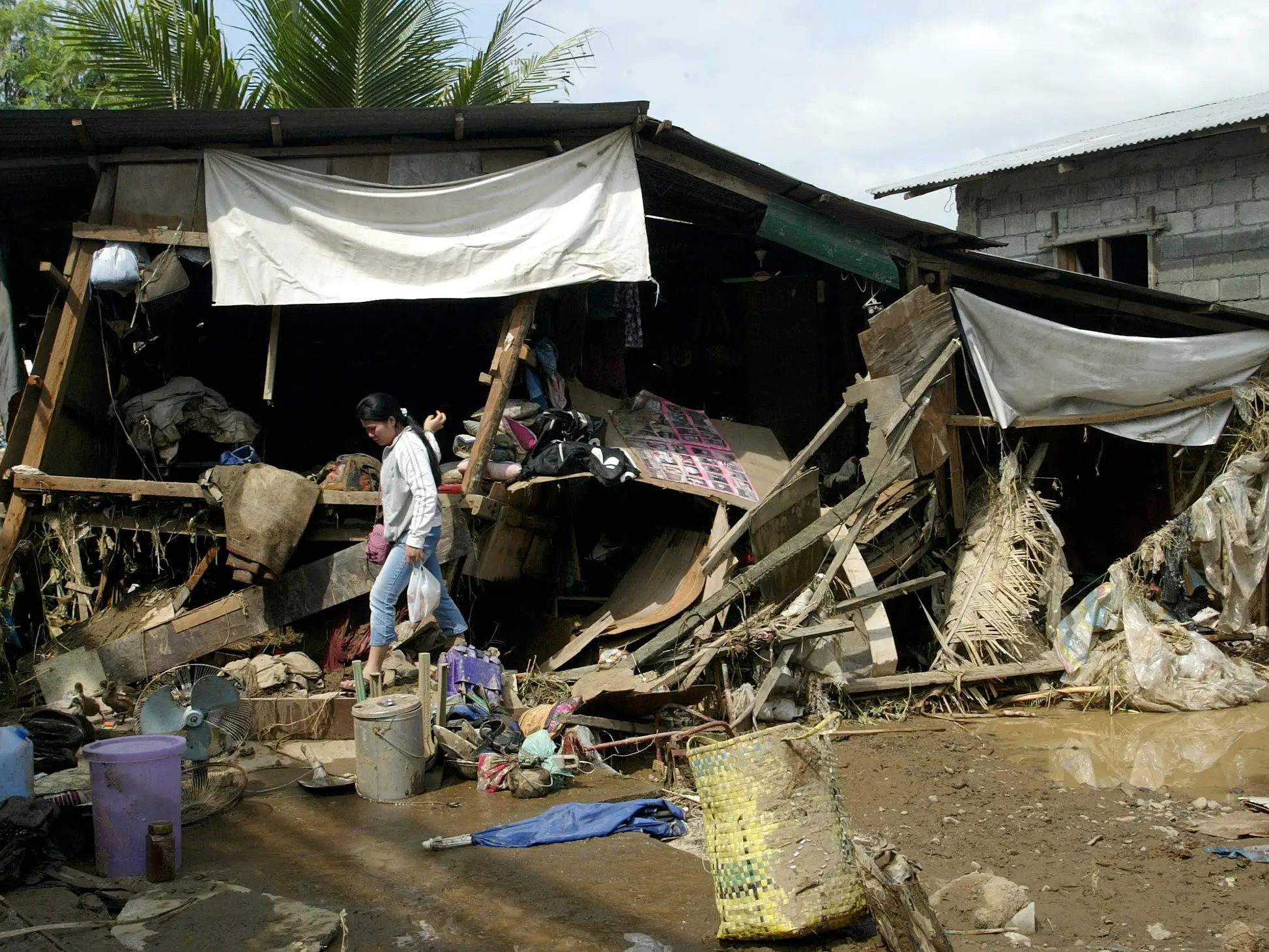 A flood victim leaves her wrecked home a day after the tropical depression Winnie hit the village of San Jose in the province of Rizal, November 30, 2004