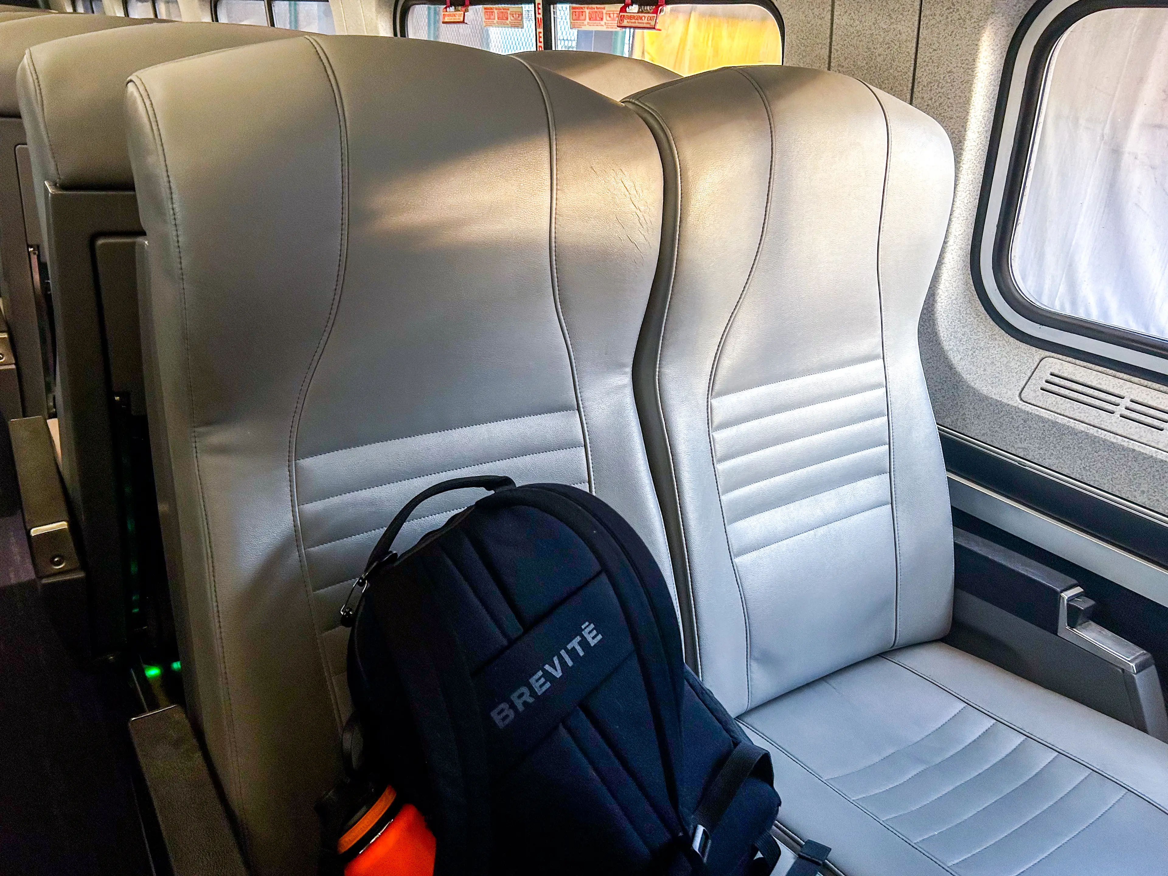 A backpack on a gray seat on an Amtrak train