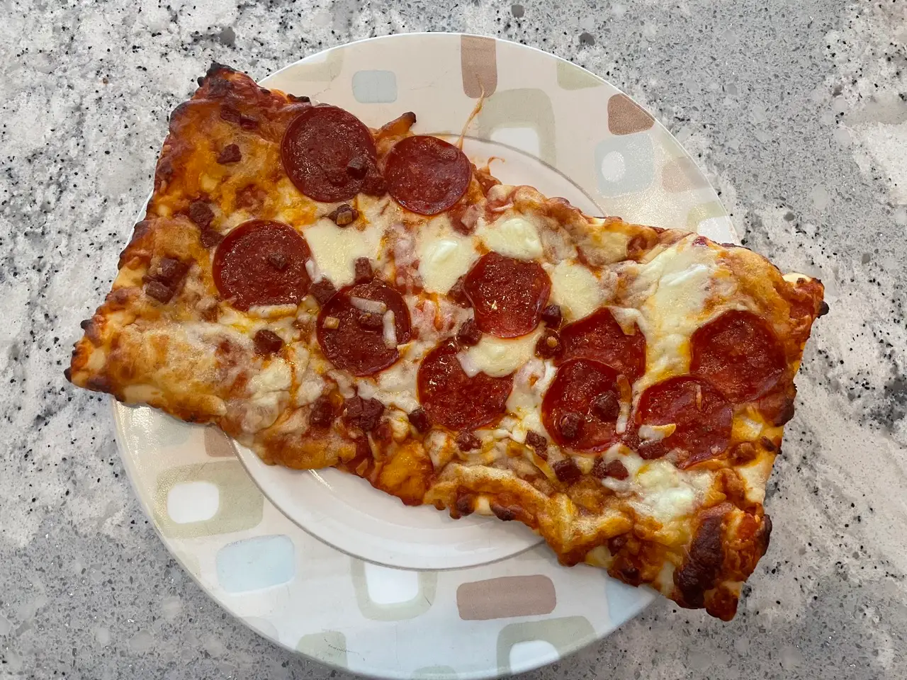 Rectangular flatbread pizza topped with pepperoni, mozarella on plate