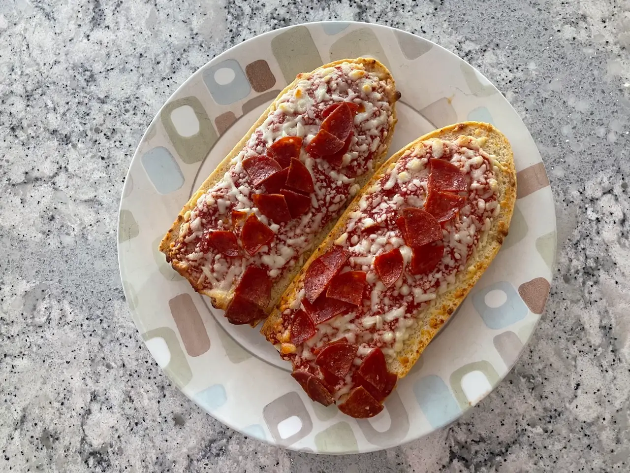 Two french bread pizzas topped with pepperoni on a plate