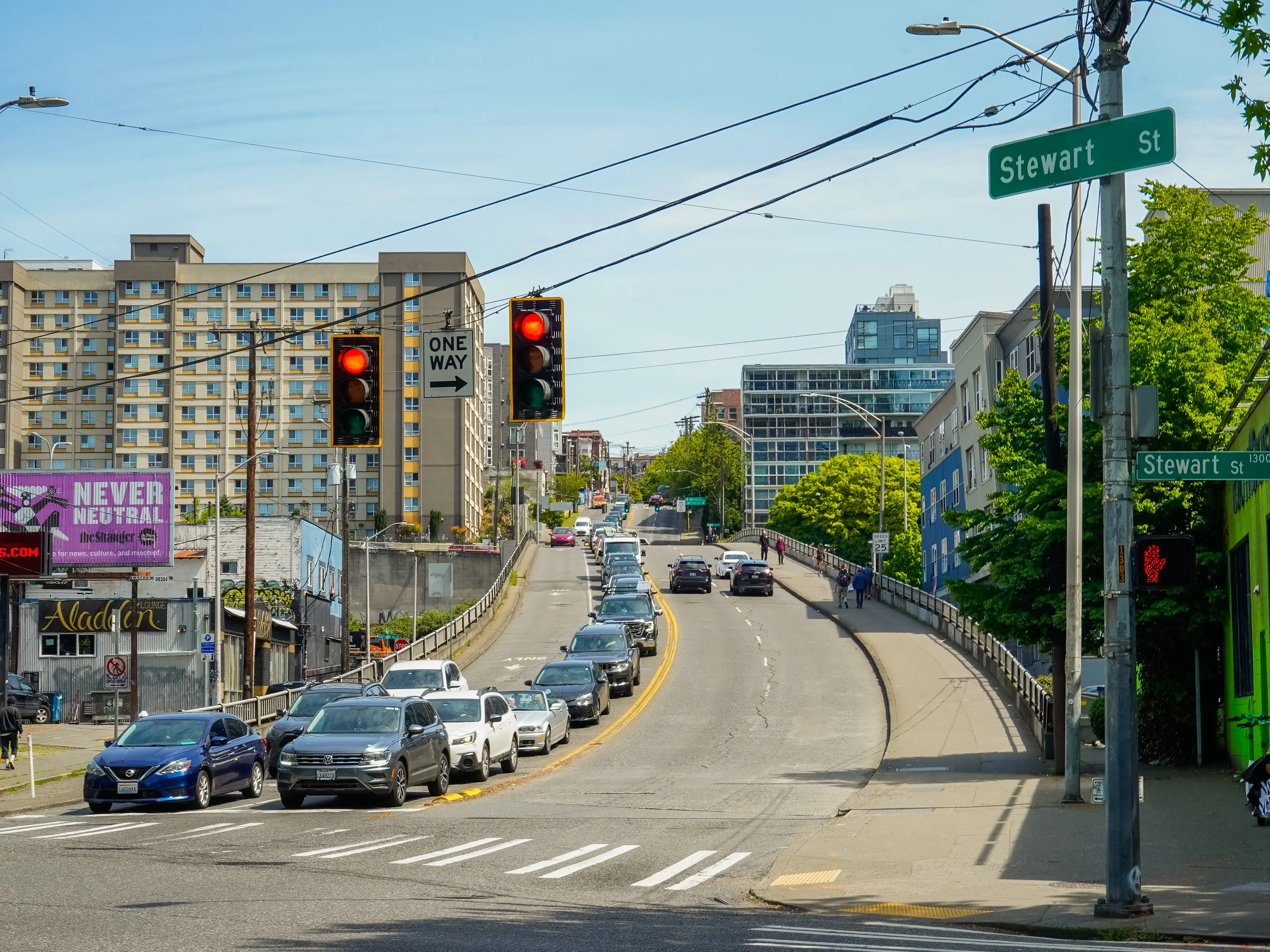 A line of cars stopped at a traffic light on a hilly street in Seattle