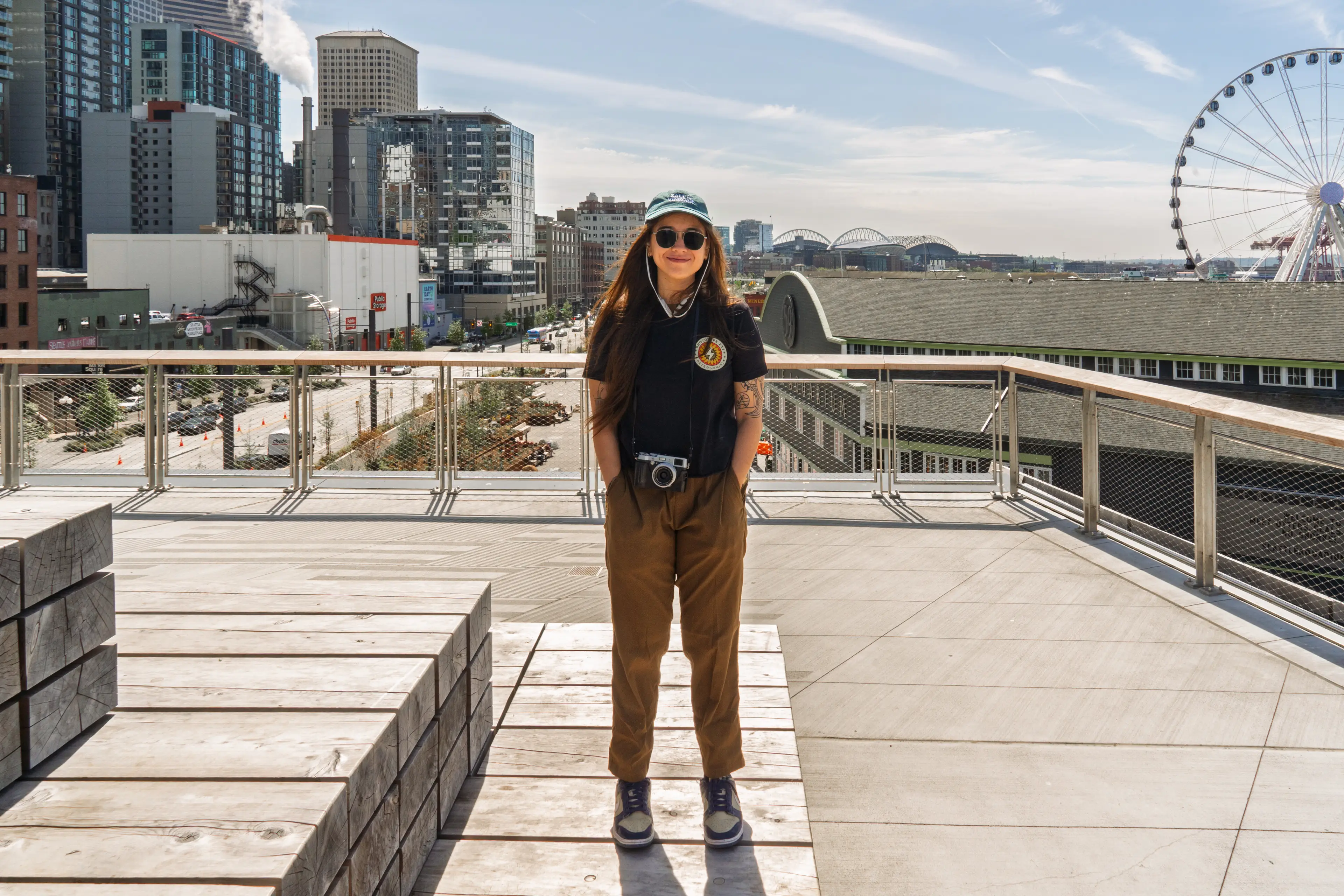 The author stands on a rooftop deck in front of city buildings with a Ferris wheel on the right