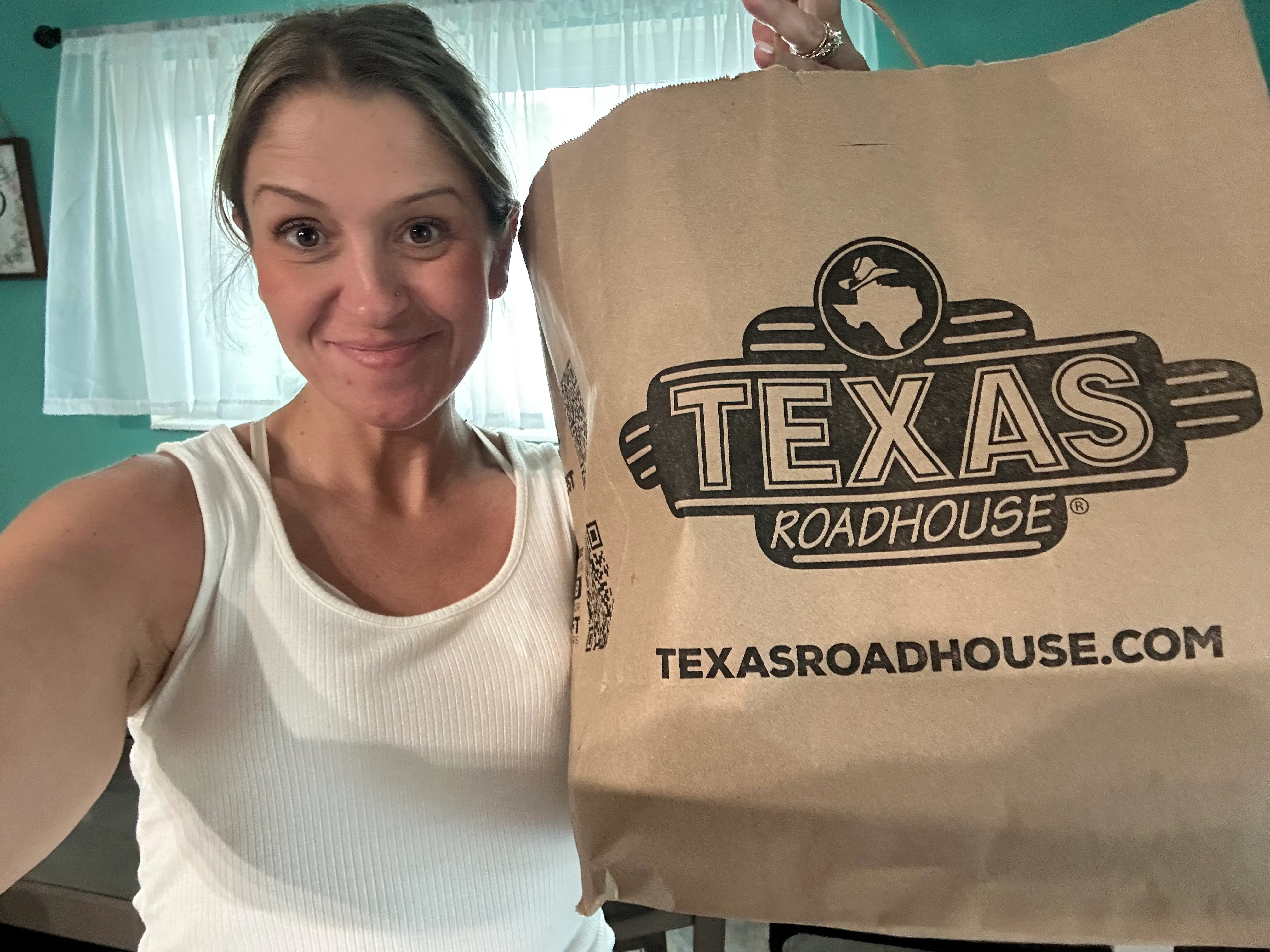 Author Terri Peters smiling holding bag from Texas Roadhouse