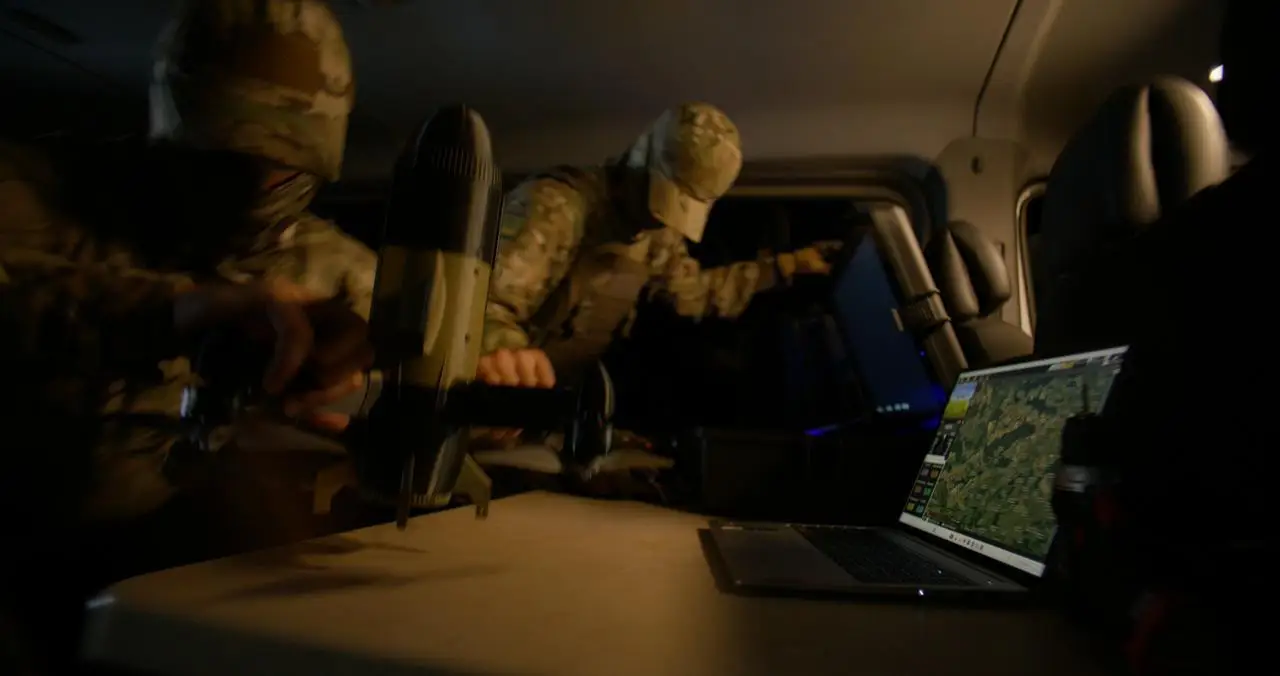 Two Ukrainian crew members of an interceptor squad prepare a Sting drone from within a truck.