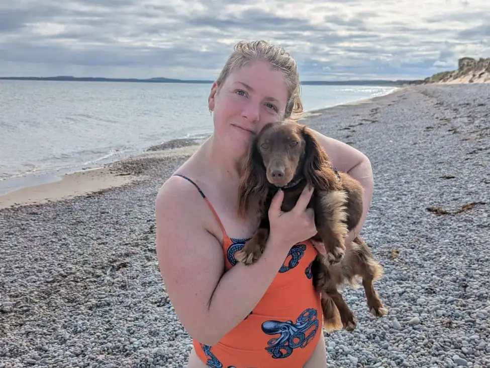 Person holding dog on beach smilnig
