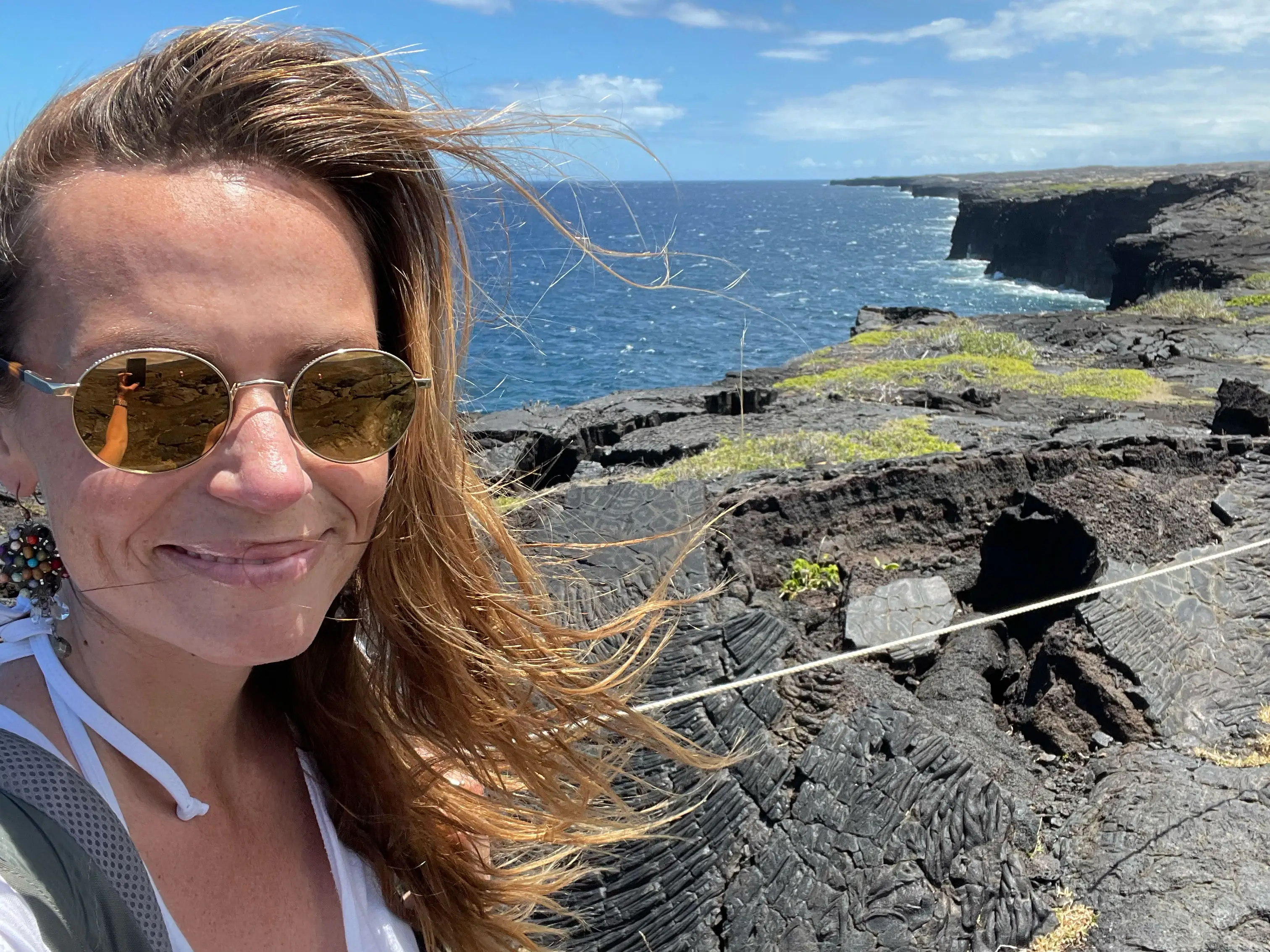 Emily stands near cliffs overlooking the ocean in Hawaii Volcanoes National Park.