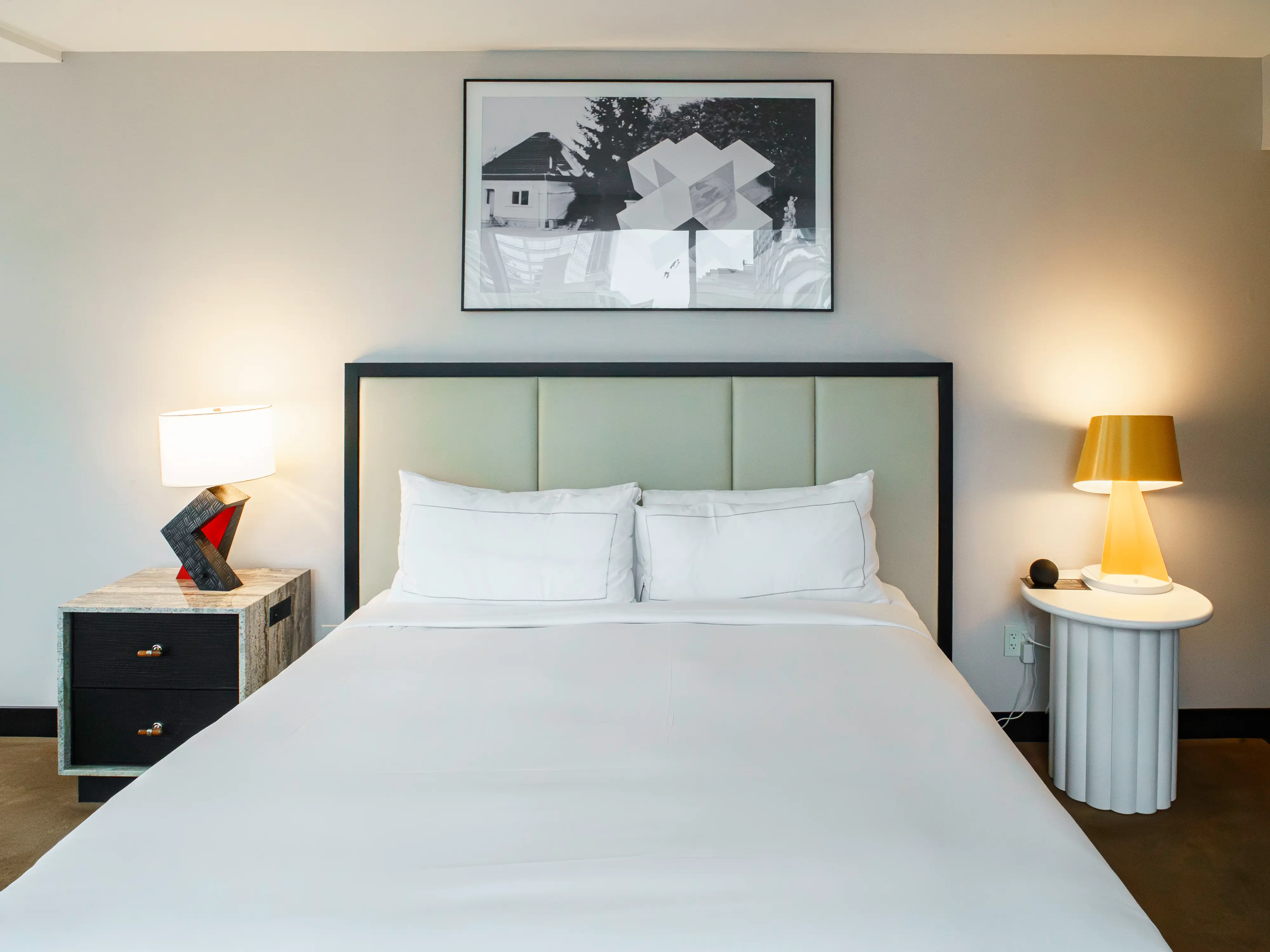 A white hotel bed with different side tables and lamps on either side