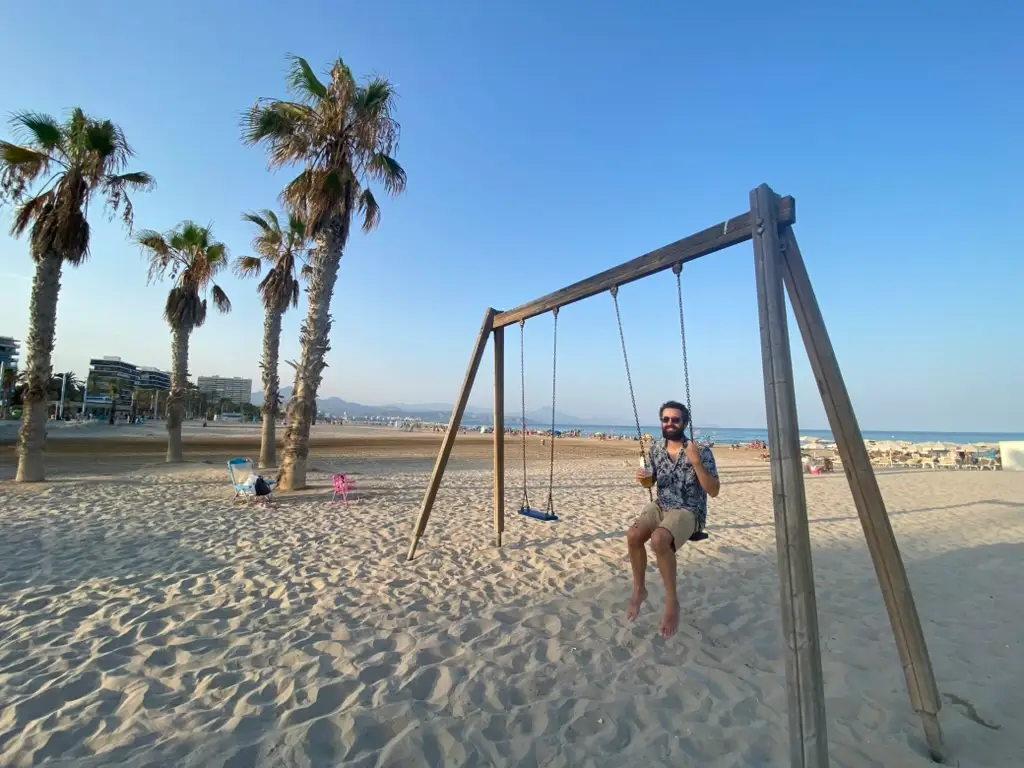 Man on swing on beach
