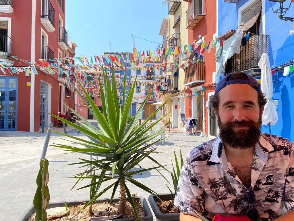 Man smiling in front of colorful buildings