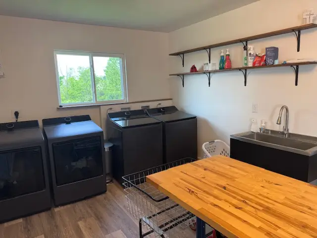 Row of washer and dryer sets with long table in front of them, window behind them