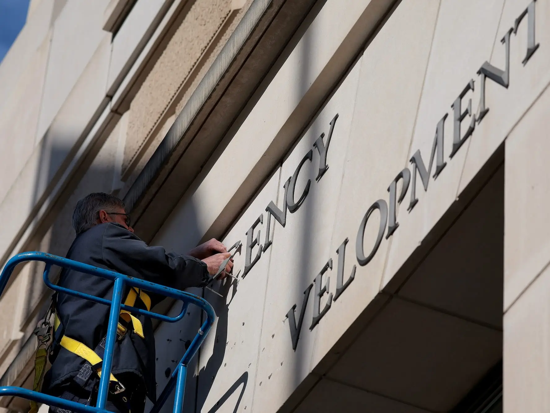 A worker removes the signage for US AID.