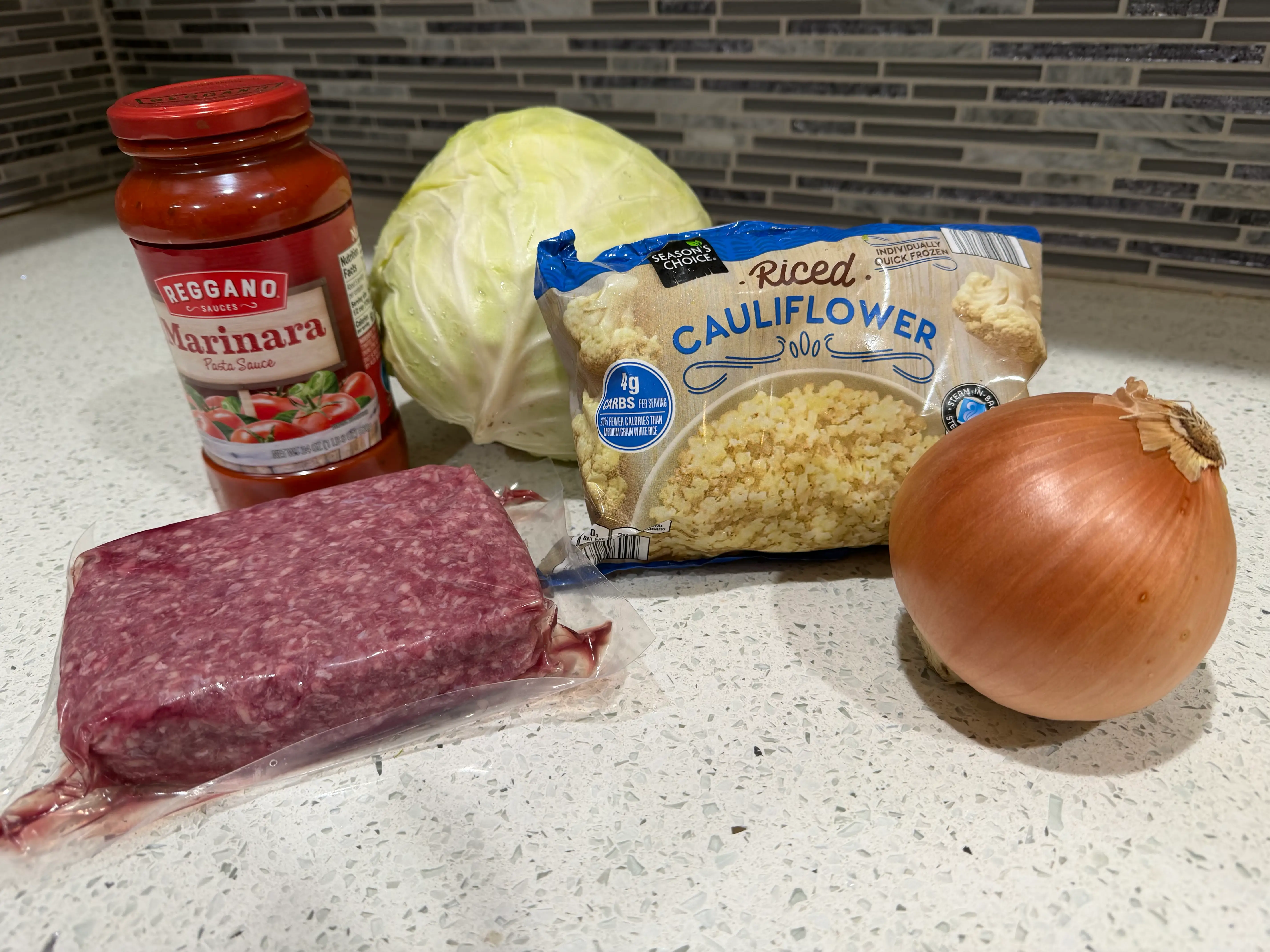 Ground meat, sauce, cabbage, cauliflower rice, onion on counter