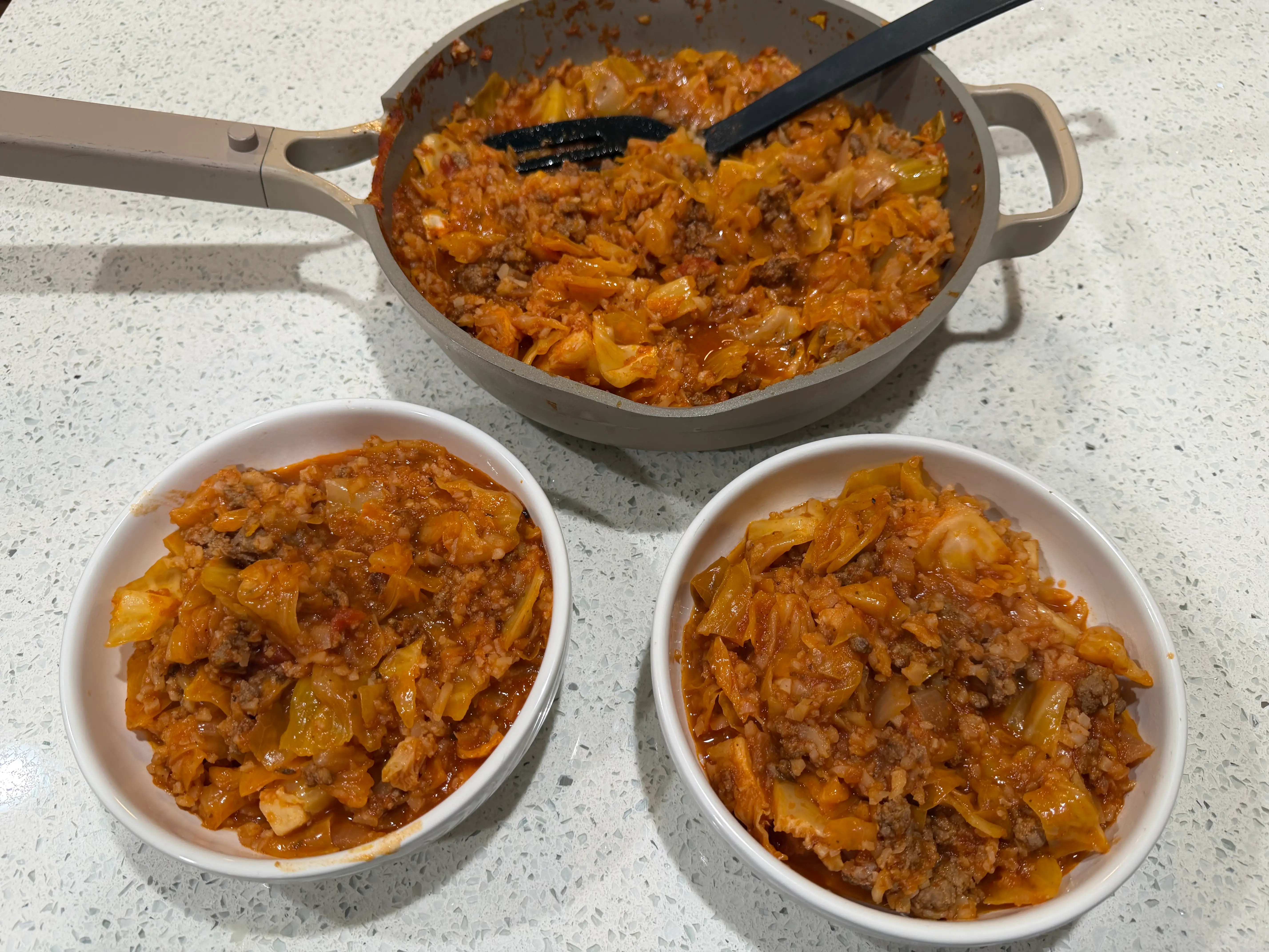 Cabbage, meat, and rice mixture in pot and two smaller bowls