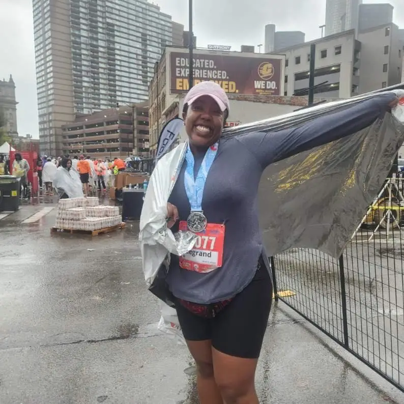 Woman smiling with marathon runner bib and medal on