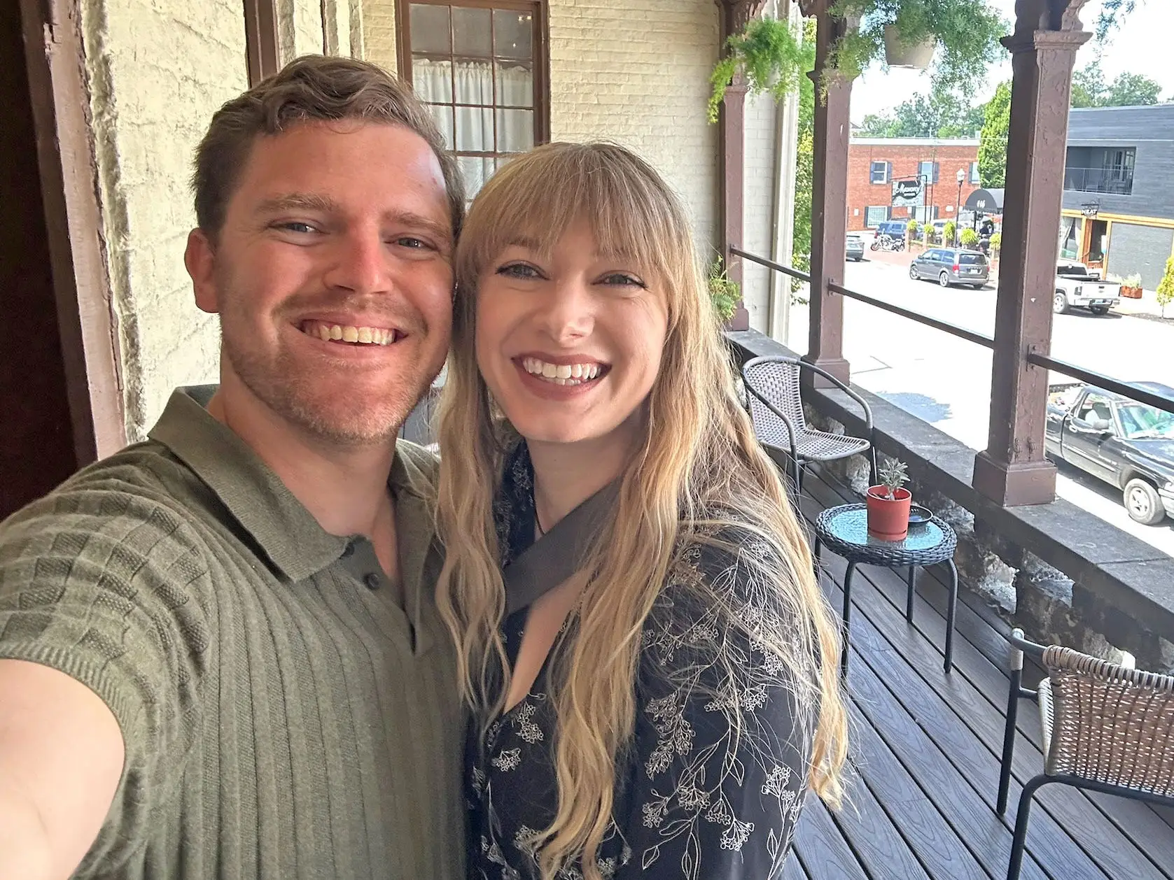 Emily and her husband pose for a selfie on a porch-style balcony.