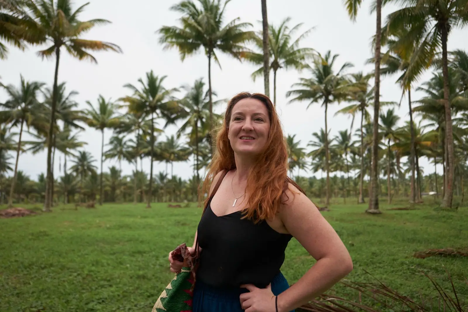 A woman in black posing uner palm trees in South America