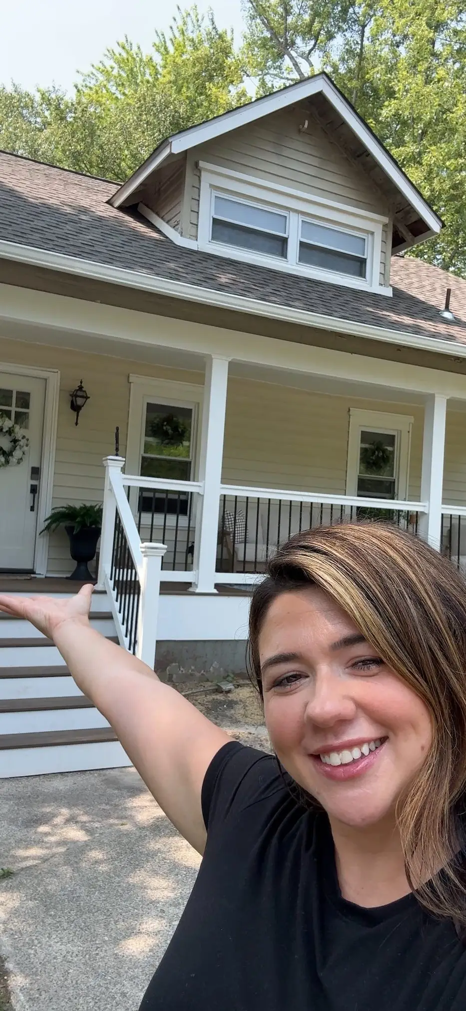 A woman taking a selfie in front of a house.