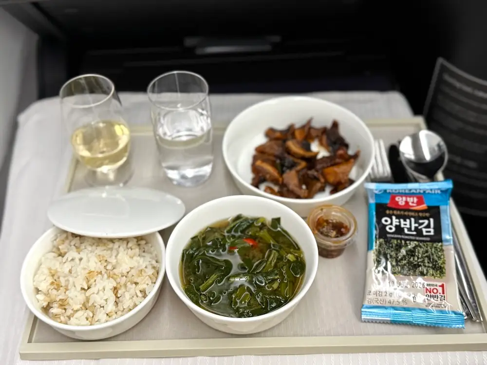 Roasted shiitake mushrooms with hot pepper sauce, rice, roasted seaweed, leafy green soup on airline tray table
