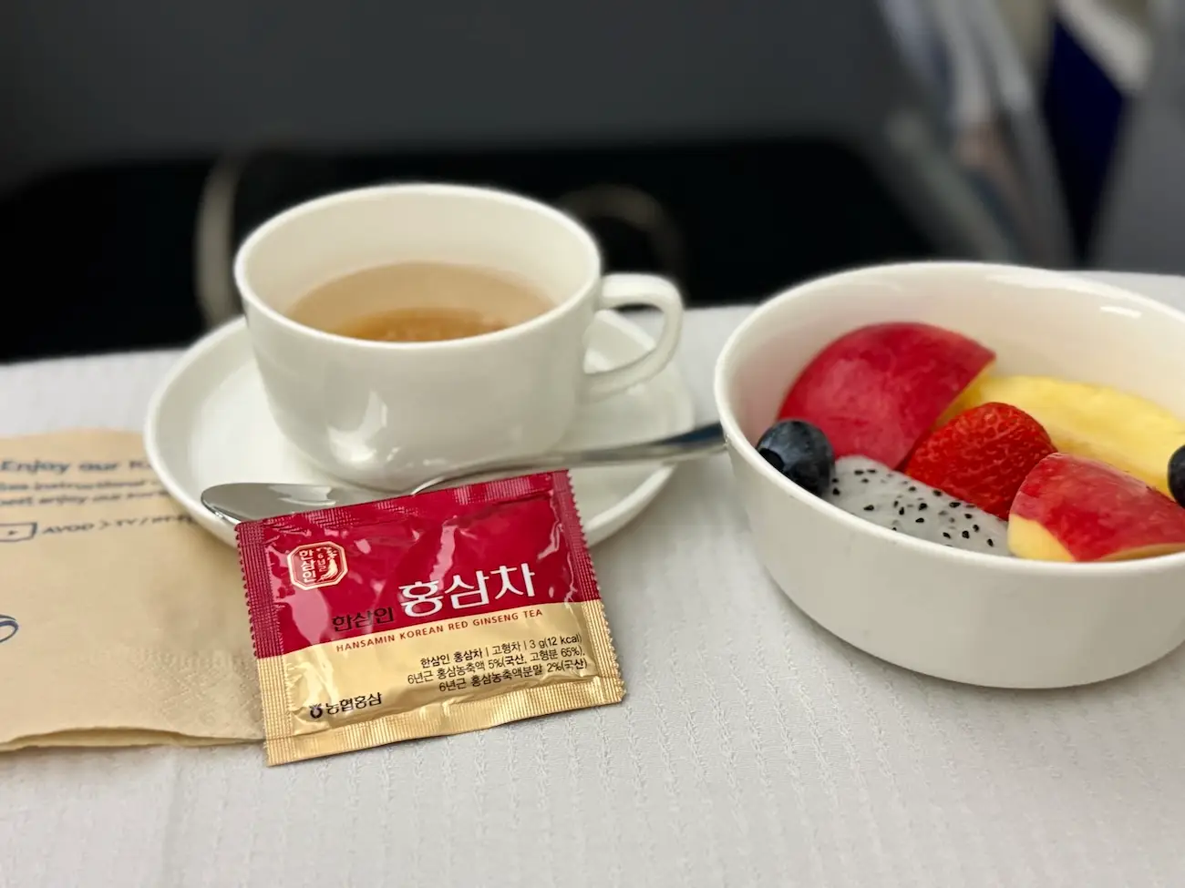 Red ginseng tea and fruit on tray table on plane
