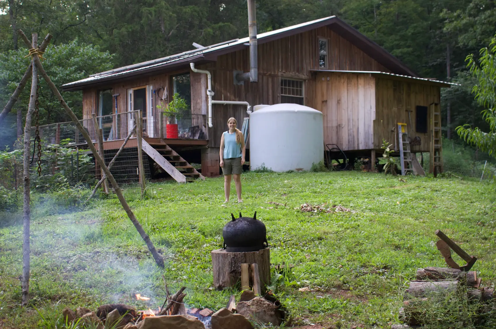 The writer standing in front of her off-grid cabin in West Virginia.
