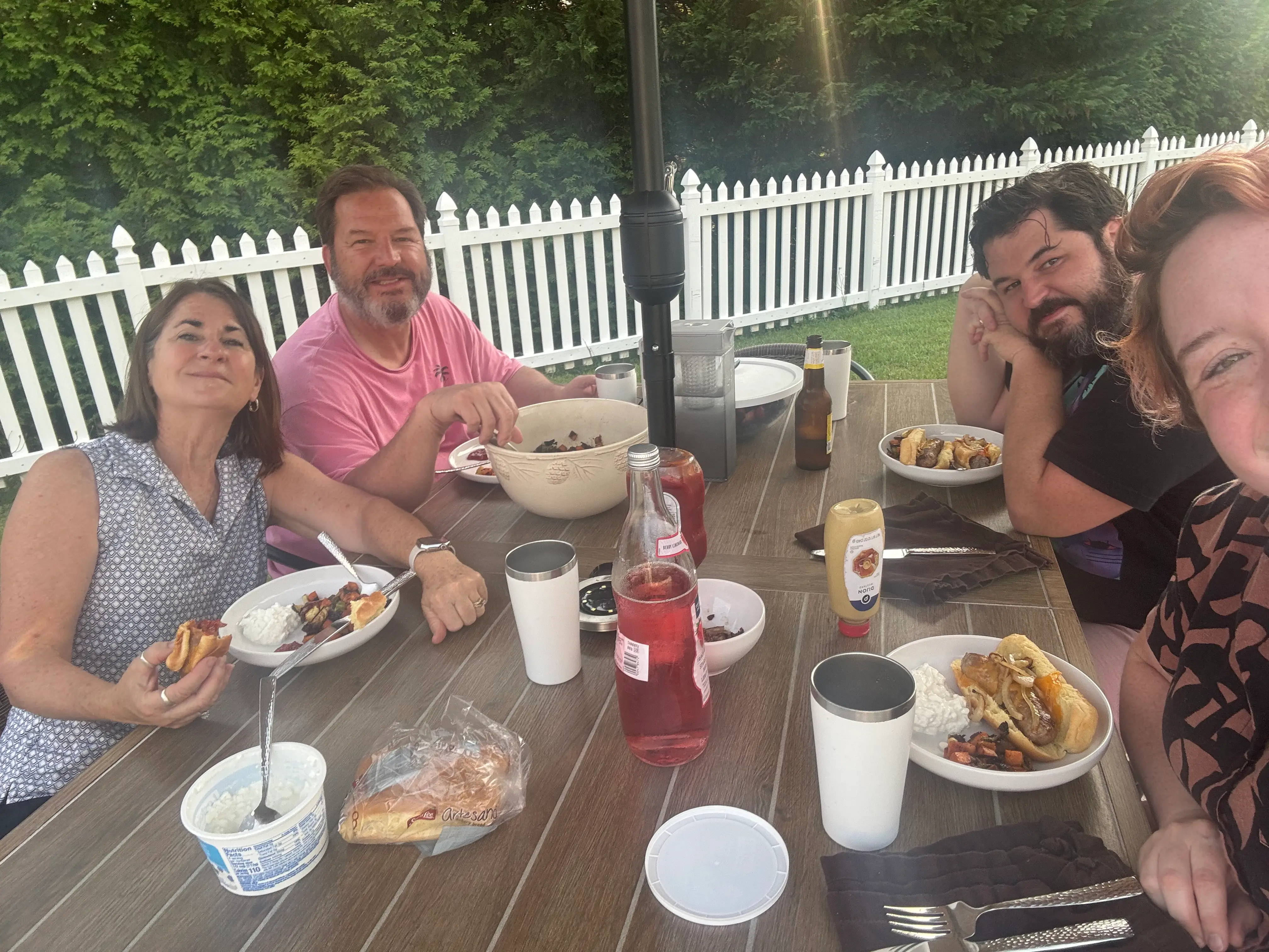 Dani and her husband share a meal with his parents at a picnic table.