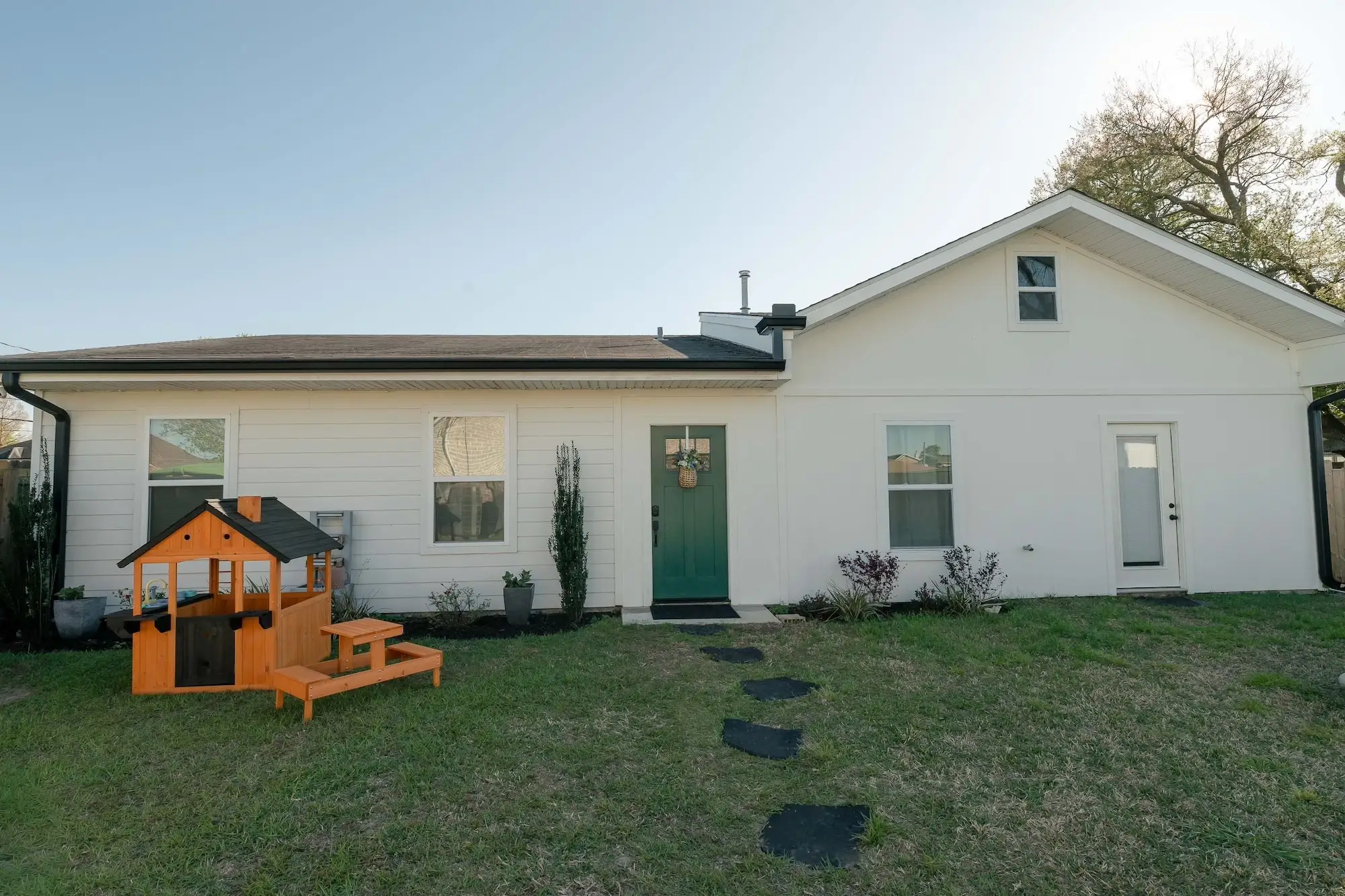A white tiny house with a green door.