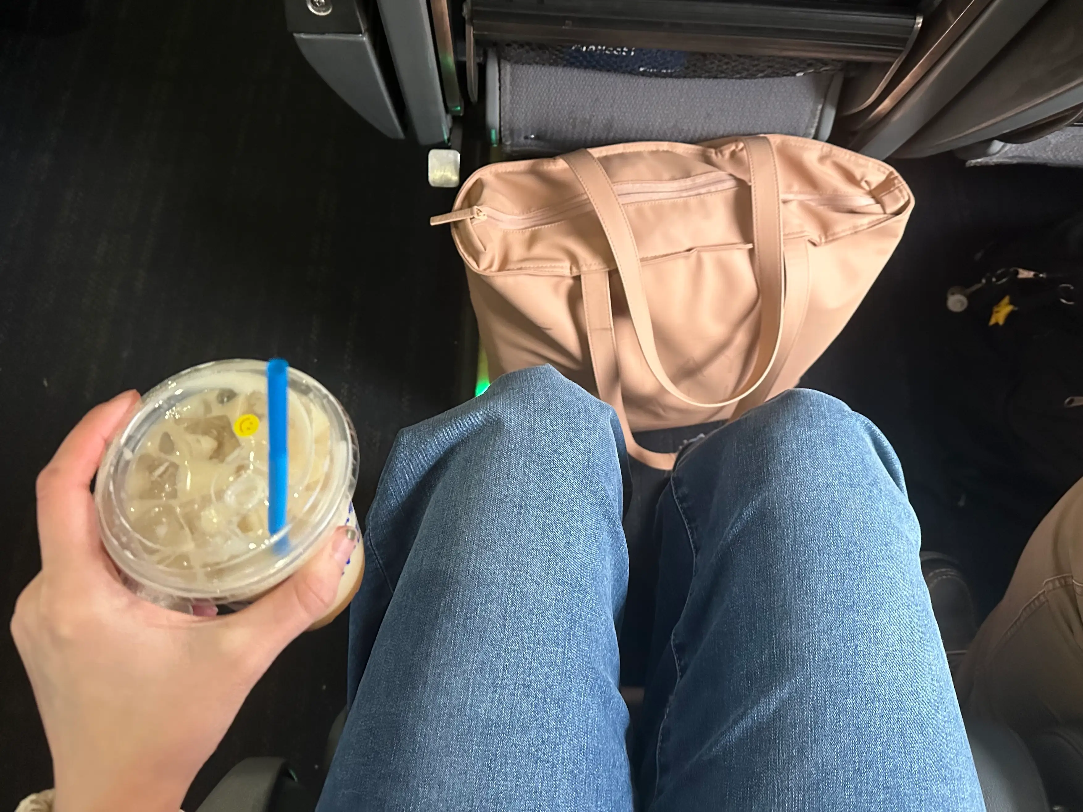 Coffee in hand with bag in front of knees on Amtrak train