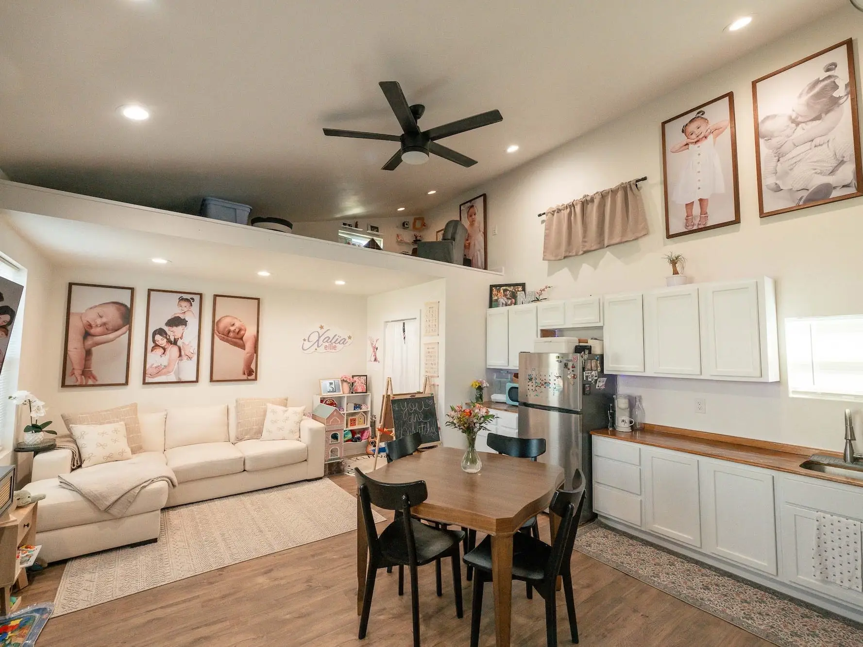 The living area of a tiny home with a ktichen, sitting area, and loft.