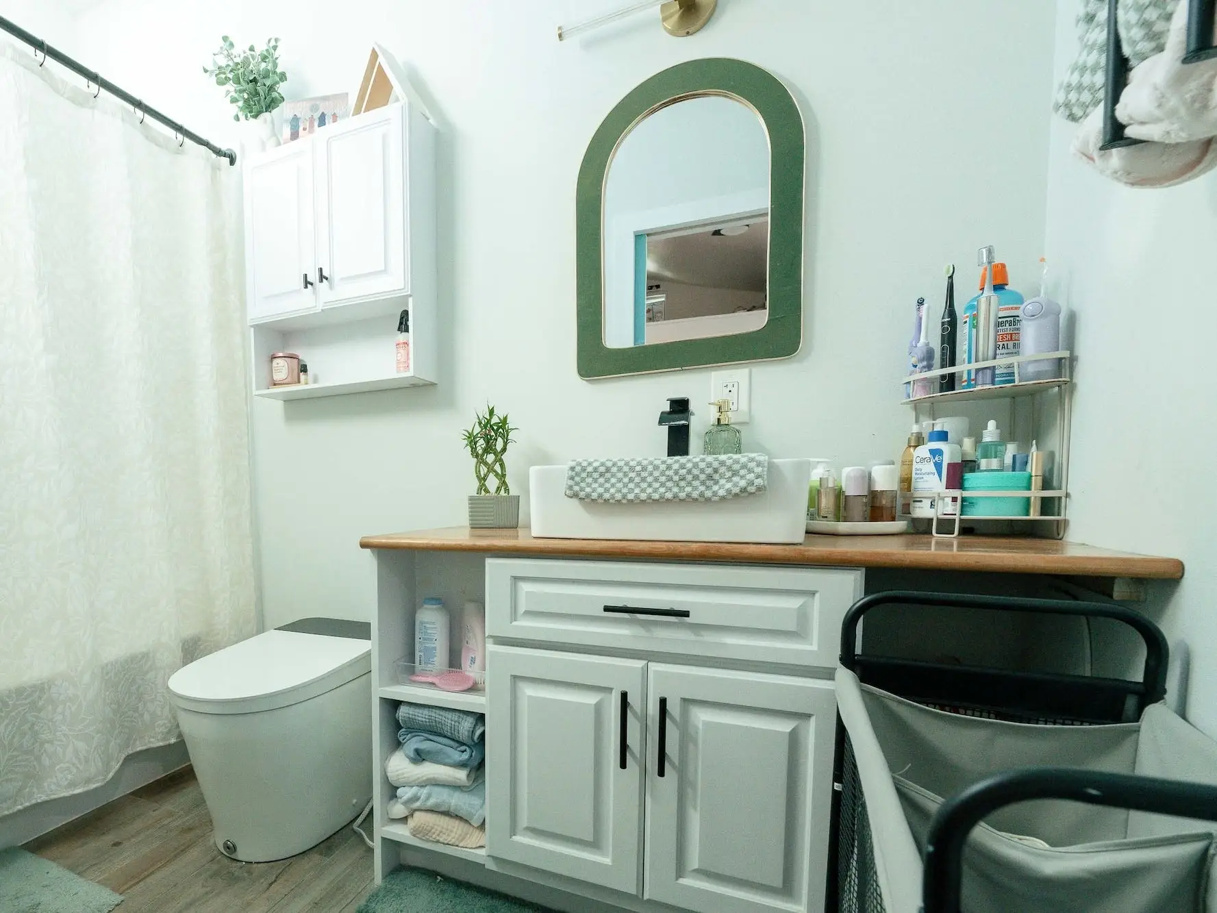 A bathroom with a large vanity and a green mirror.