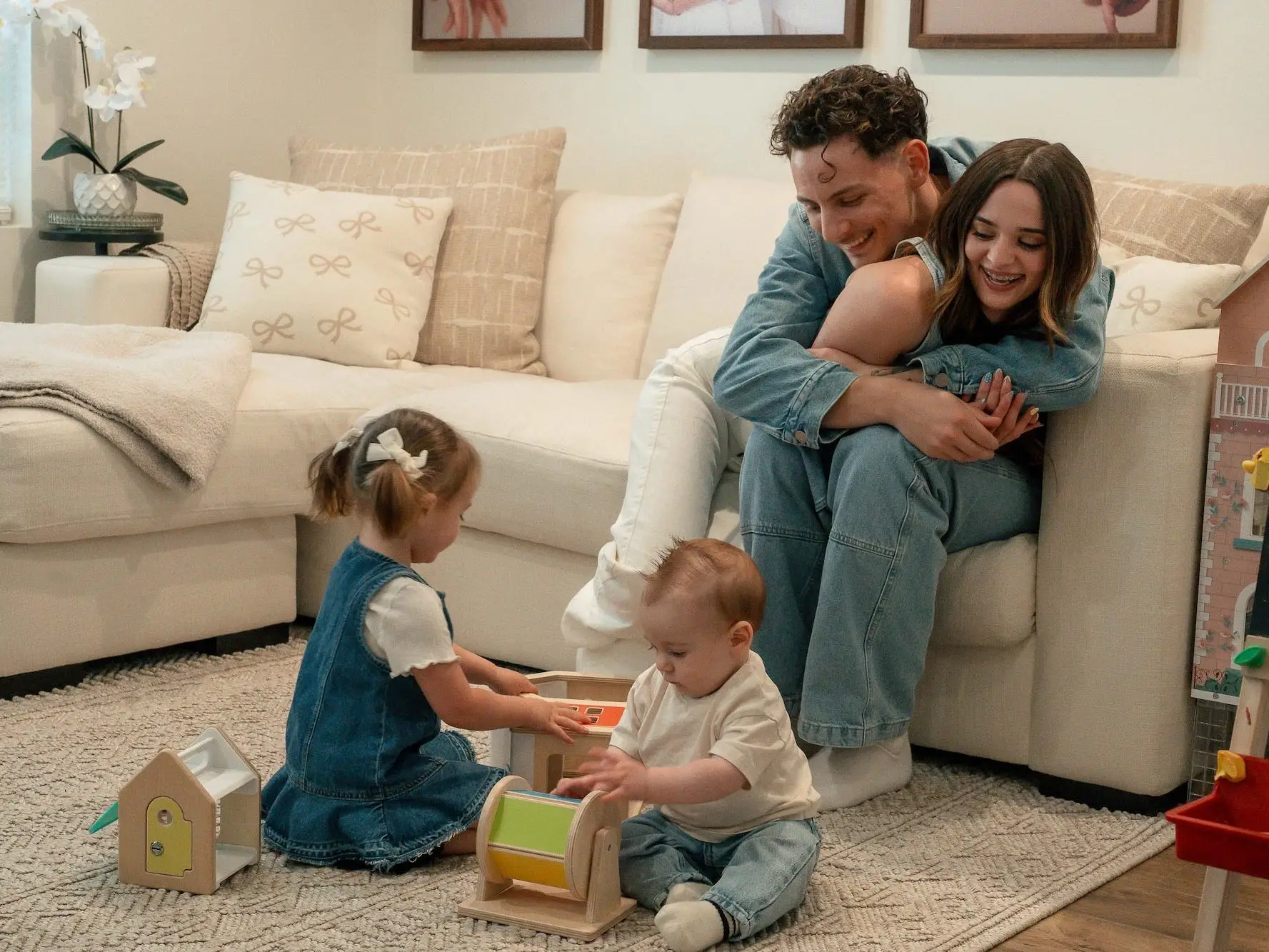 A couple hugs on a couch while their children play.