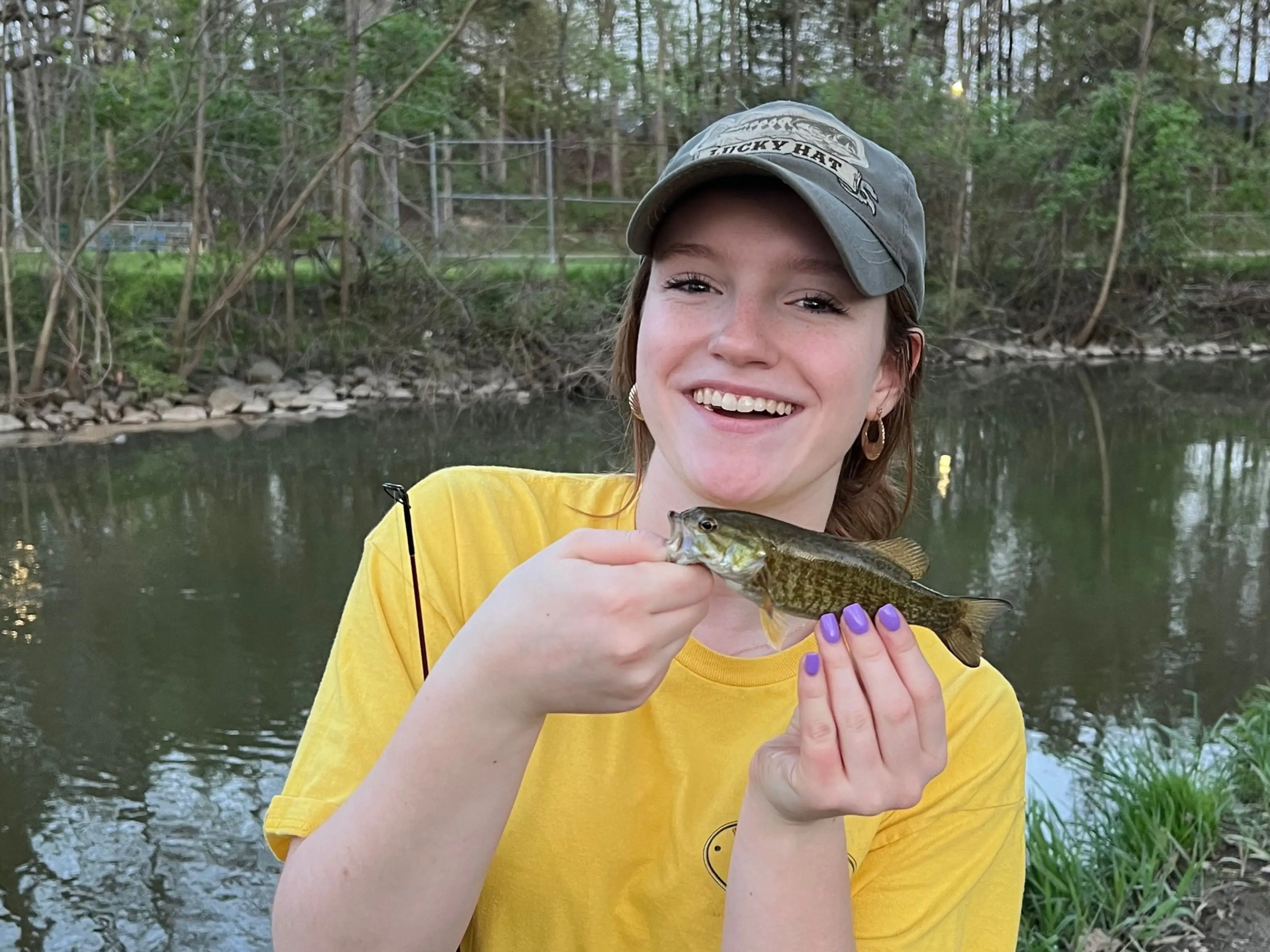 The author's daughter poses with a small fish she caught while next to water.