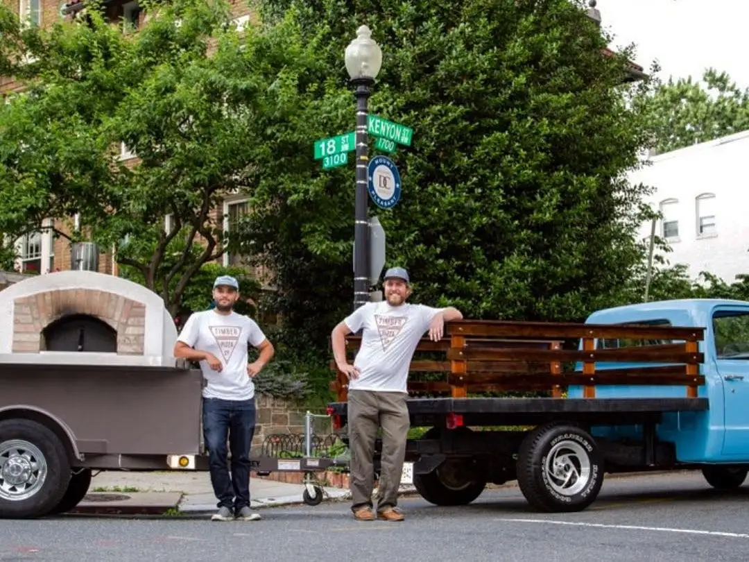 Men standing next to blue truck