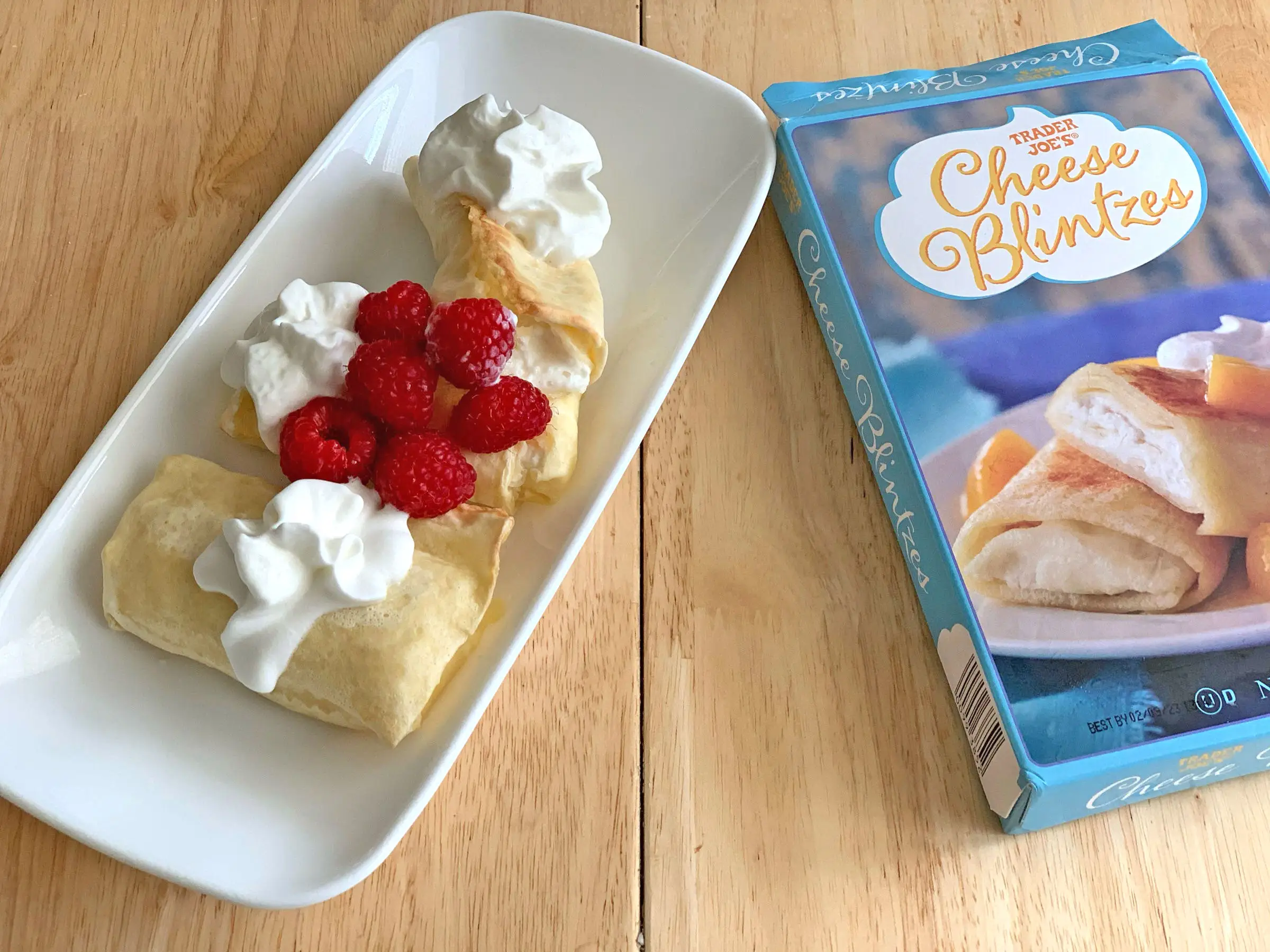 A plate of Trader Joe's blintzes beside a blue box.