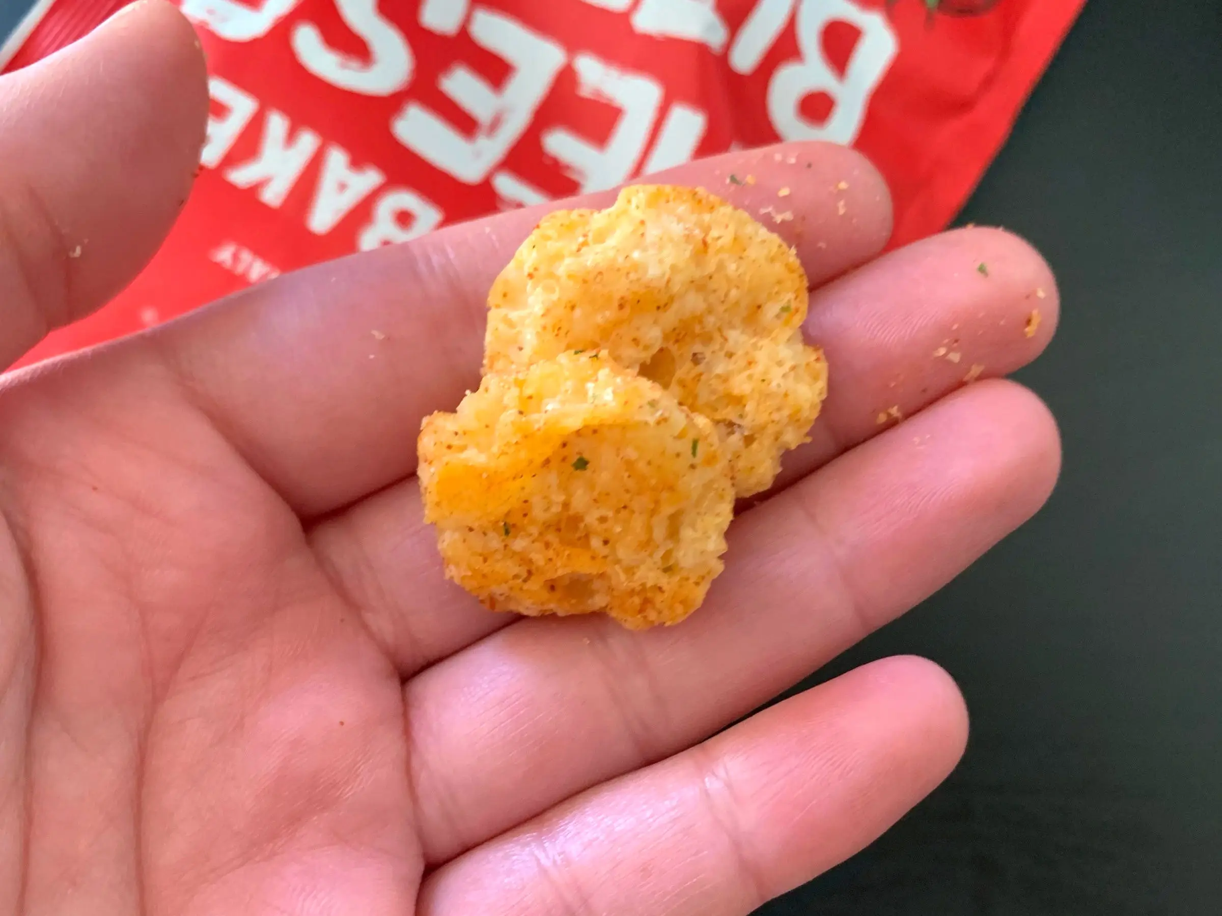 A hand holding some two Trader Joe's cheese bites.