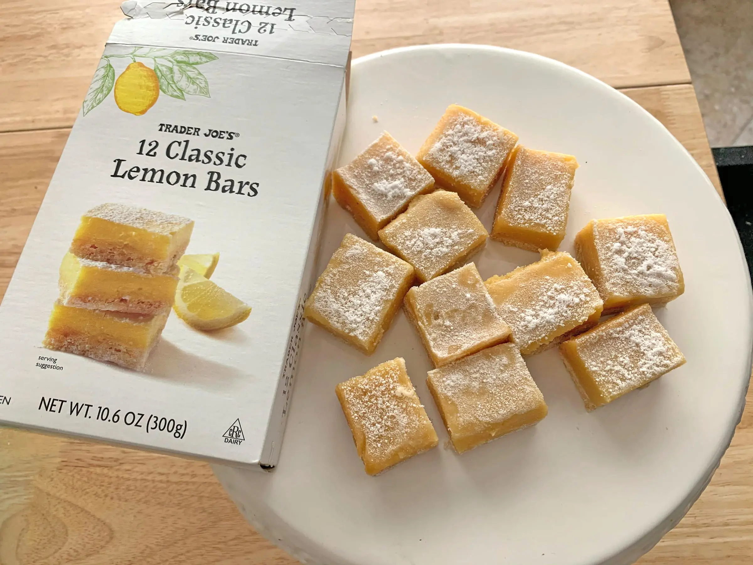 Trader Joe's lemon bars on a white plate, next to the box the product came in.