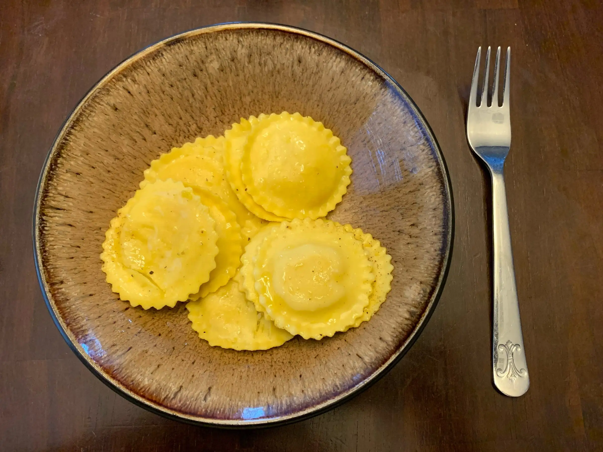 A fork next to a plate of lemon ravioli.
