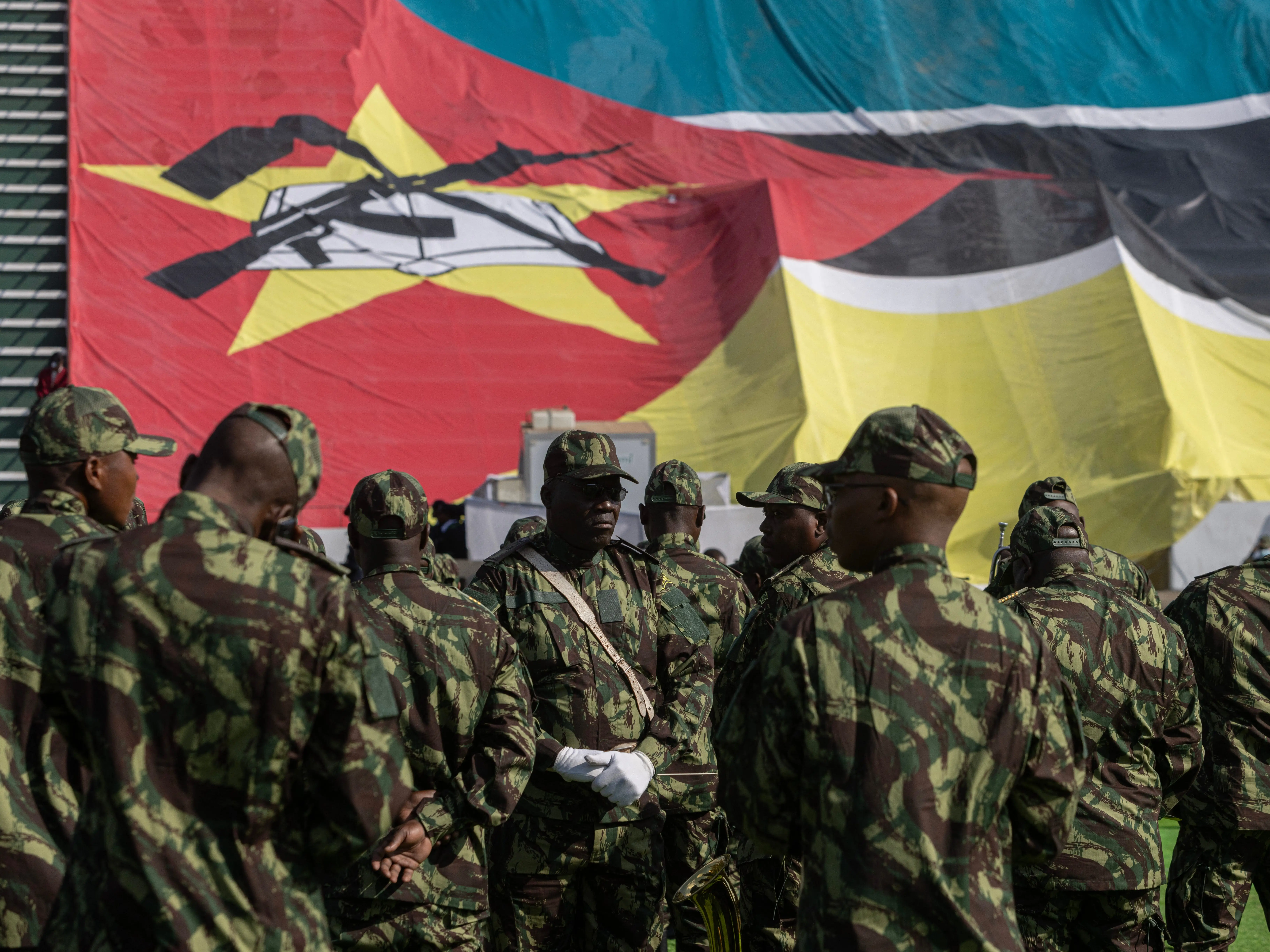 Members of the Mozambique military in front of the national flag.