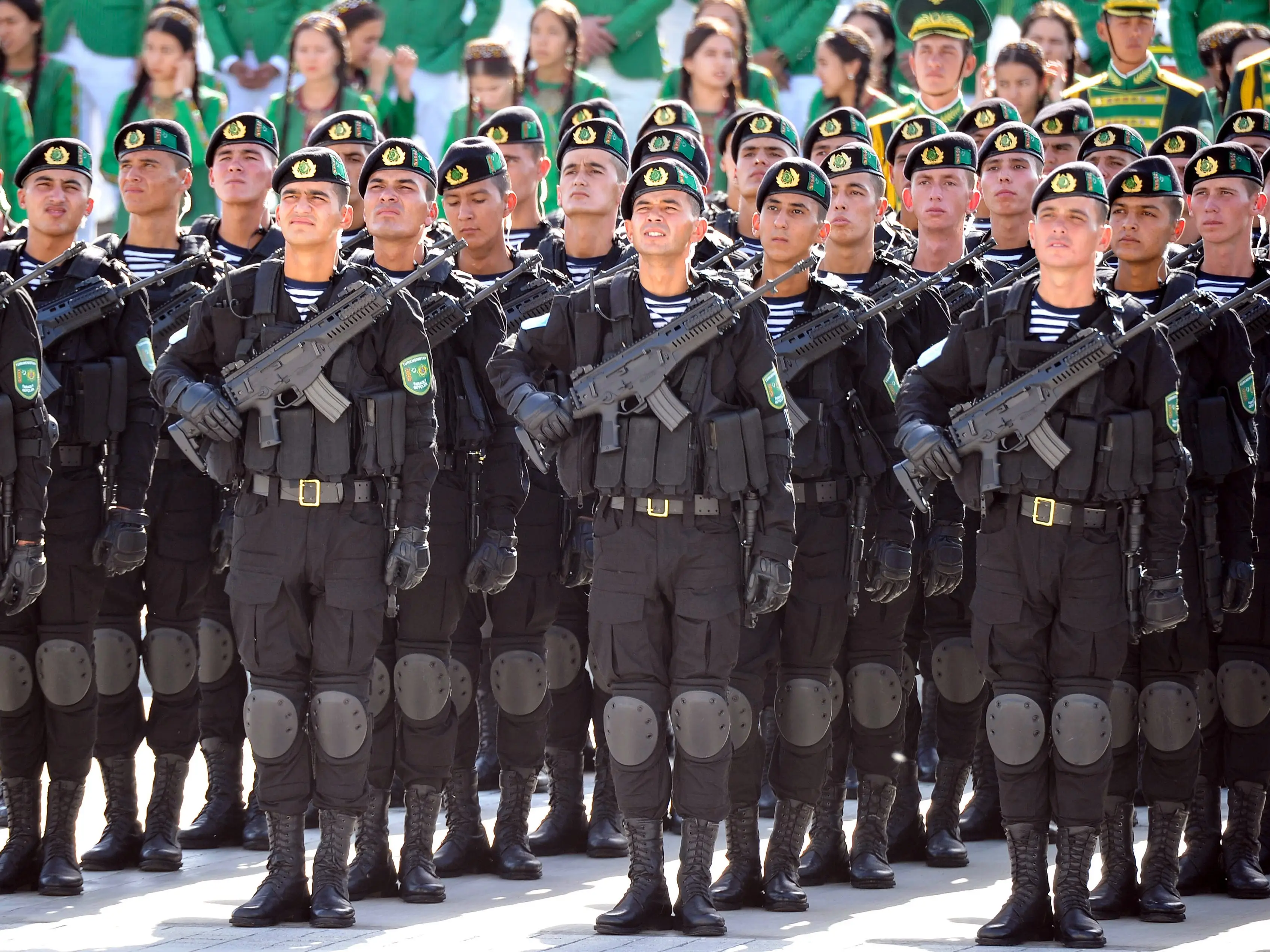 Turkmen servicemen stand with rifles during a military parade.