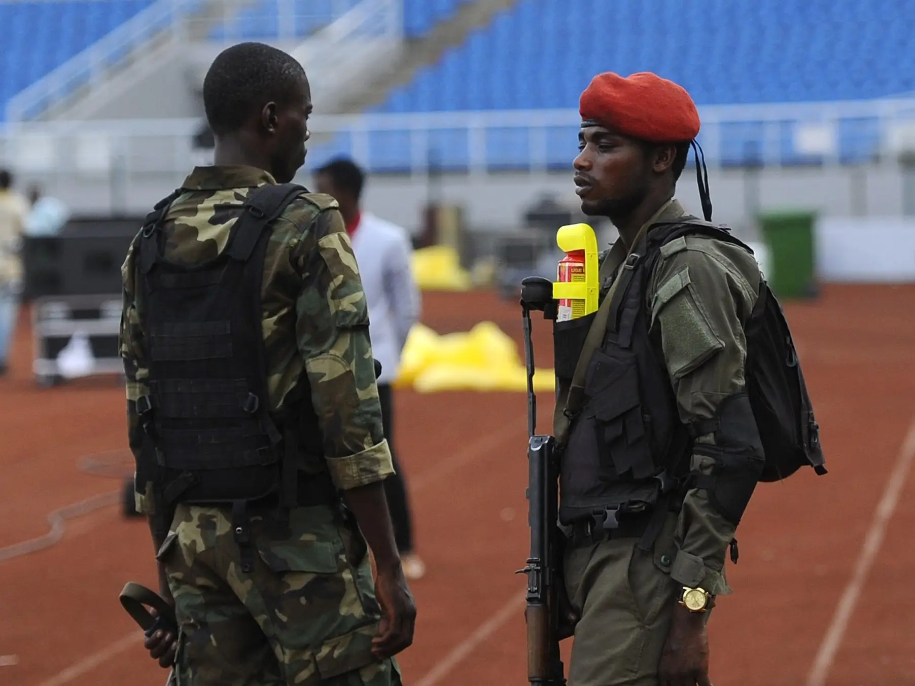 Military guards in Equatorial Guinea talking in a stadium while holding rifles.