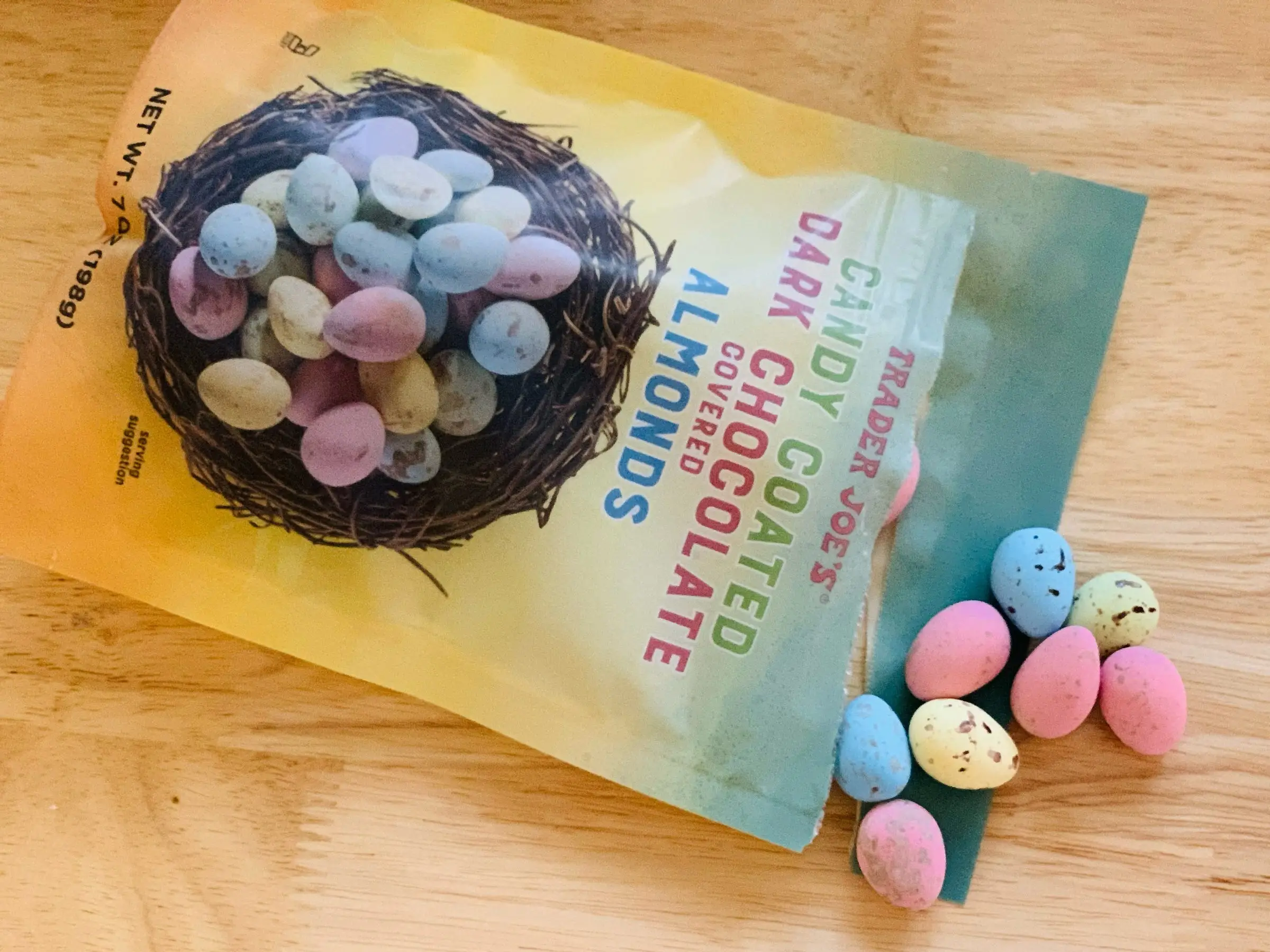 A few candy-coated almonds spill out of the bag they came in.