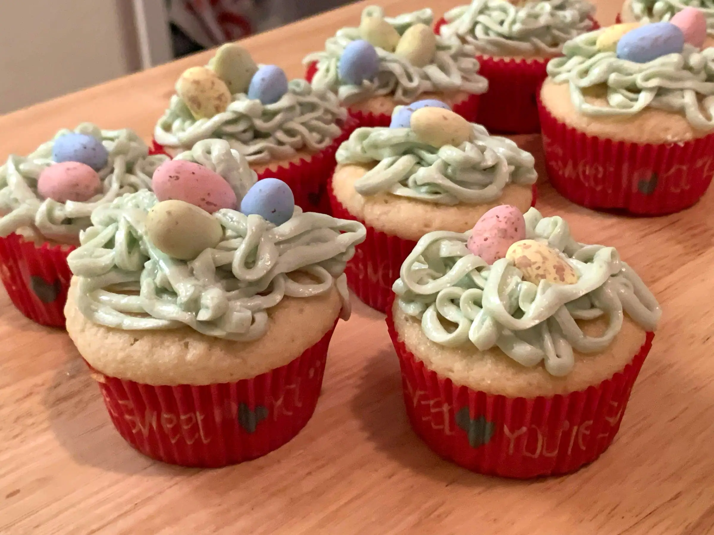 Cupcakes topped with green, stringy frosting, and candy eggs.