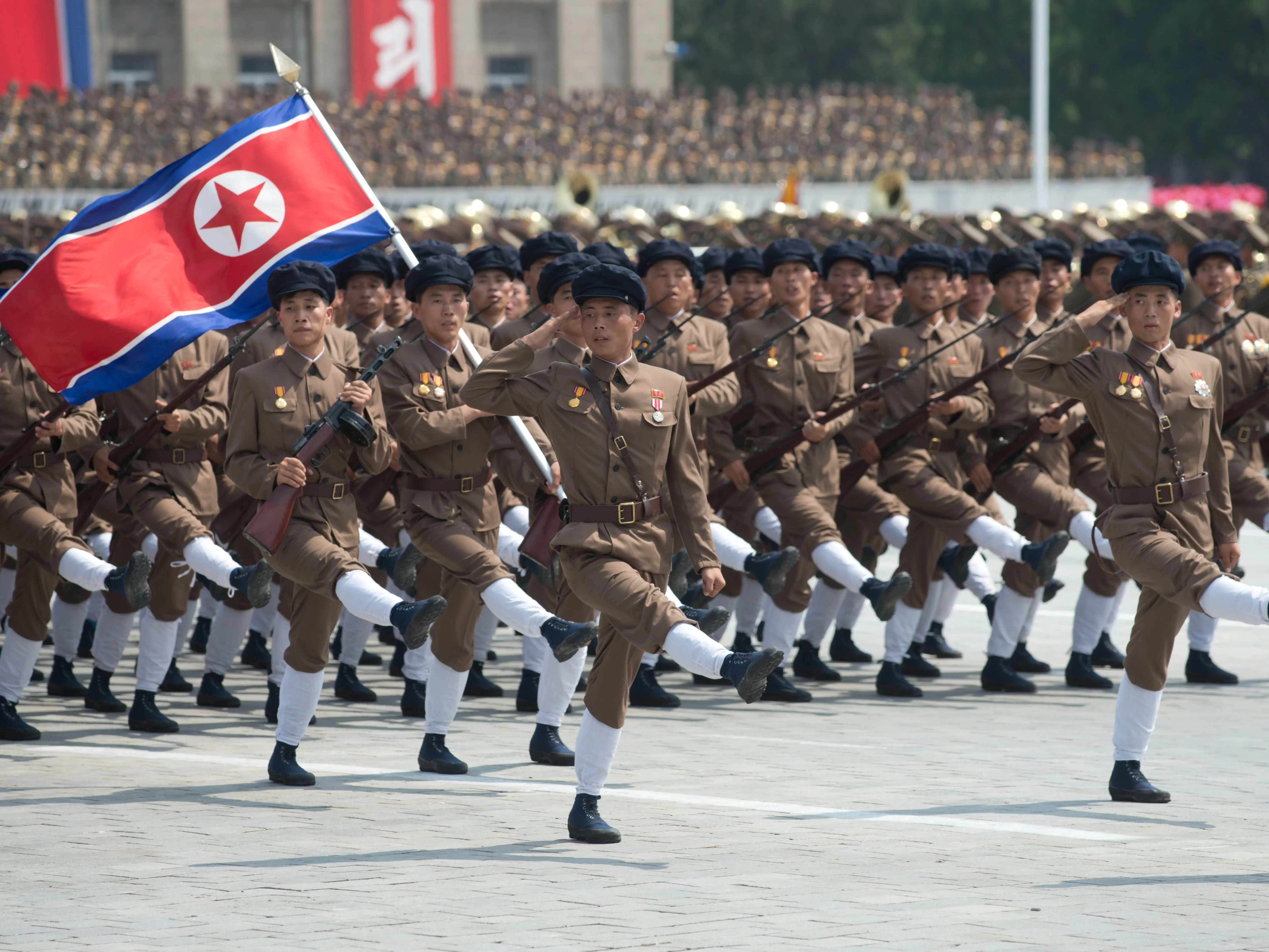 North Korean soldiers march in a parade with the national flag.