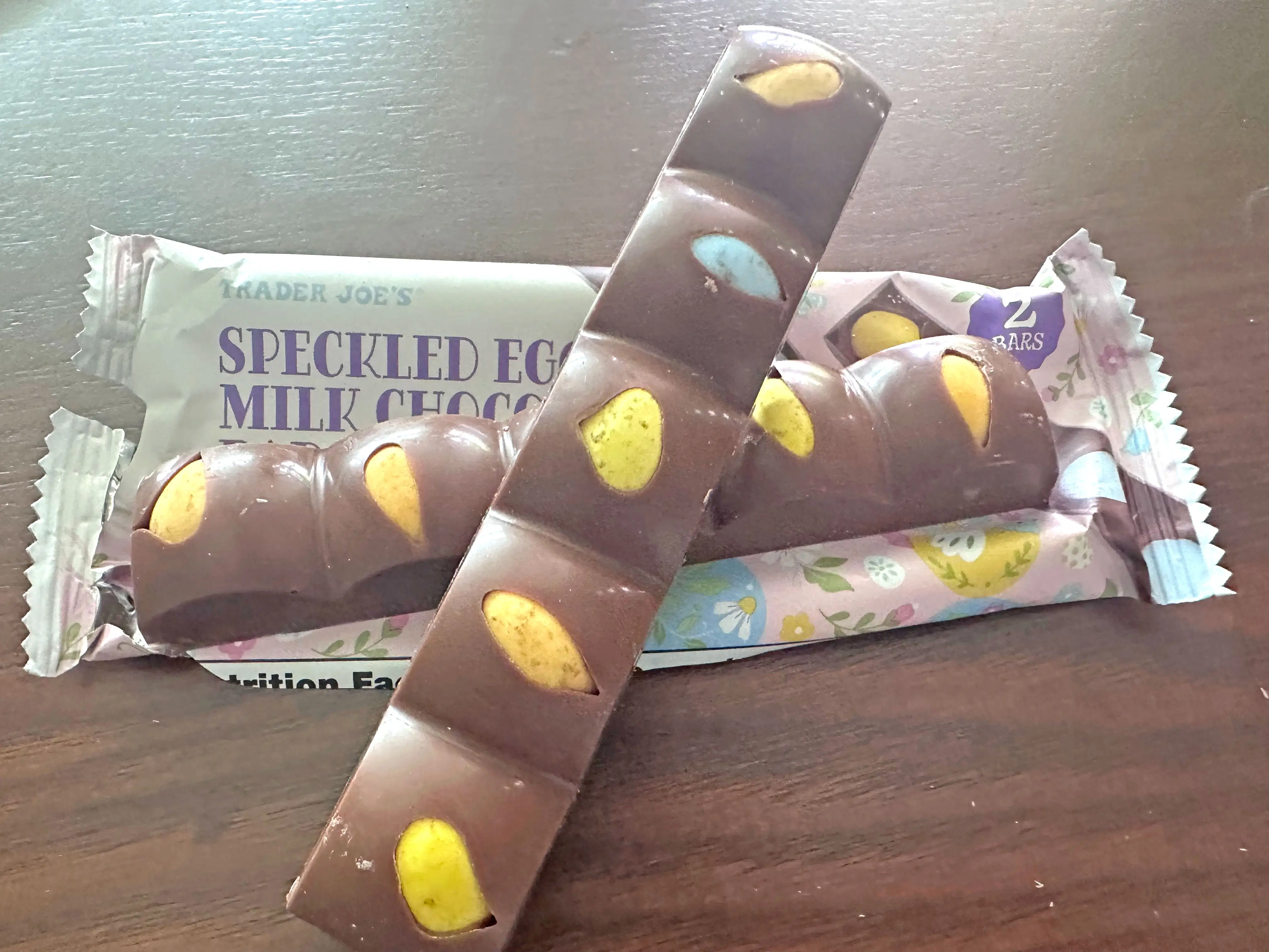 Two chocolate bars with speckled eggs inside on top of the wrapper that the product came in.