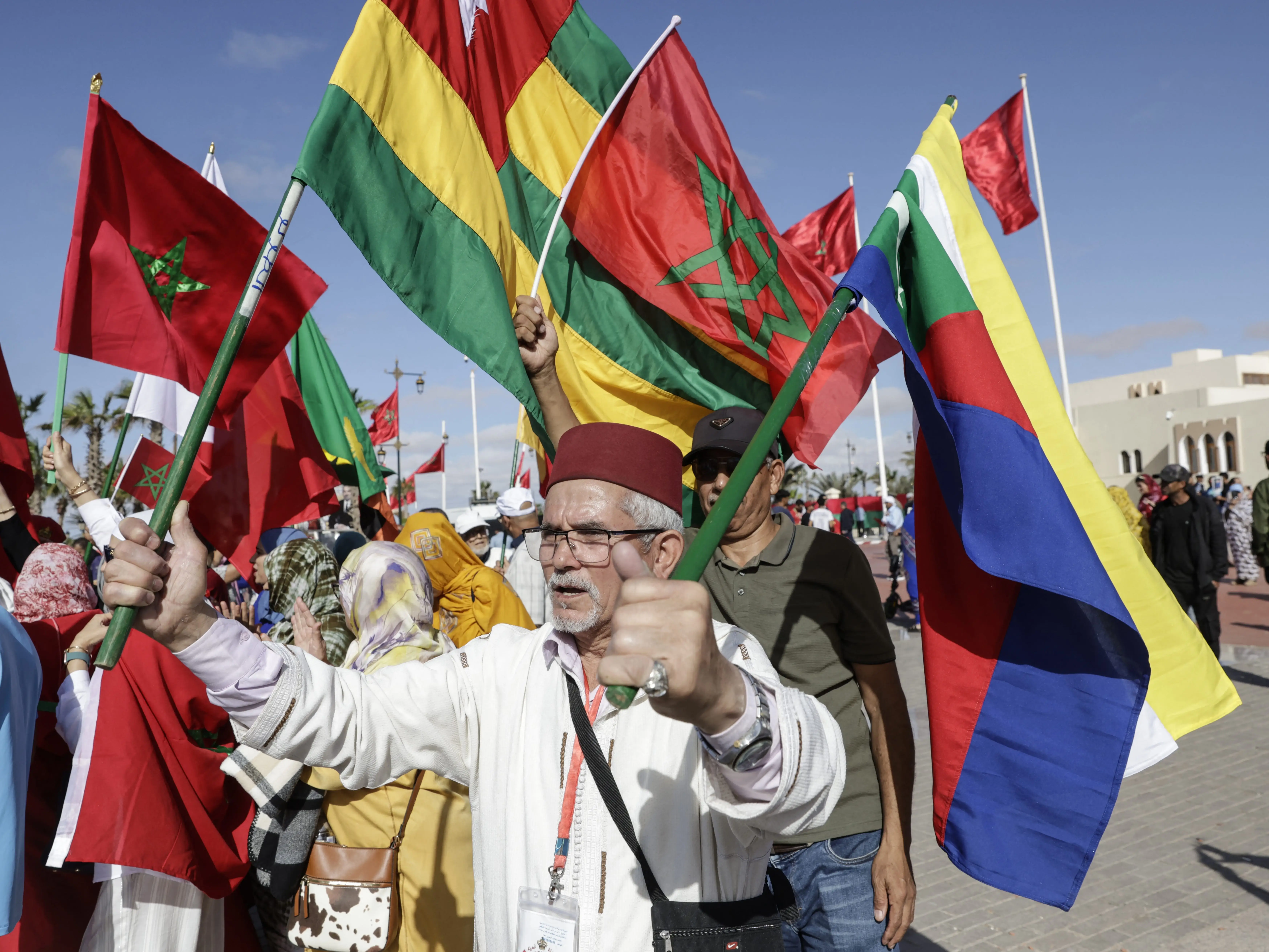A man in Moroccan-controlled Laayoune holds multi-colored flags, including the flag or Morocco.