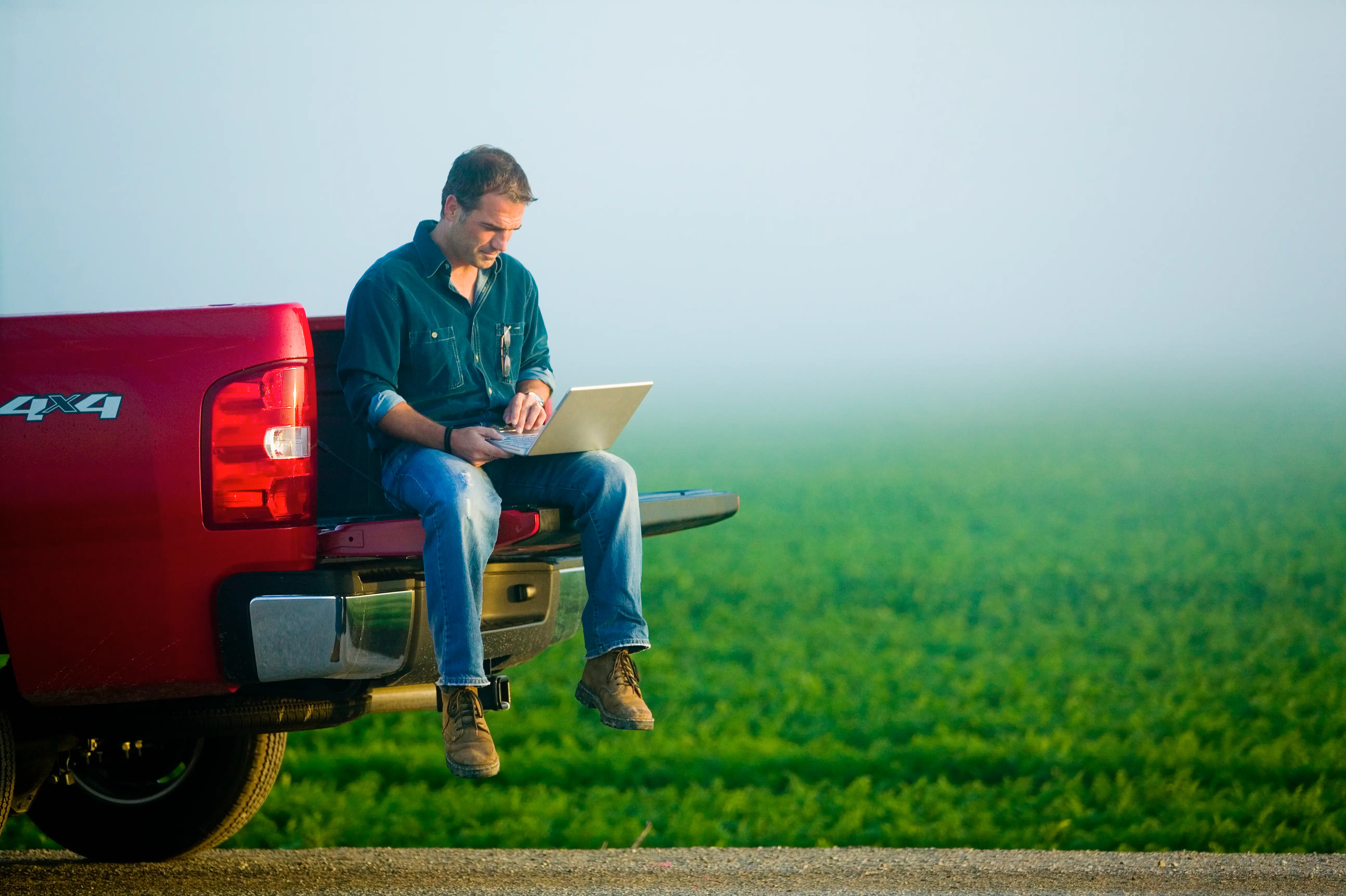 Young farmer using laptop in field