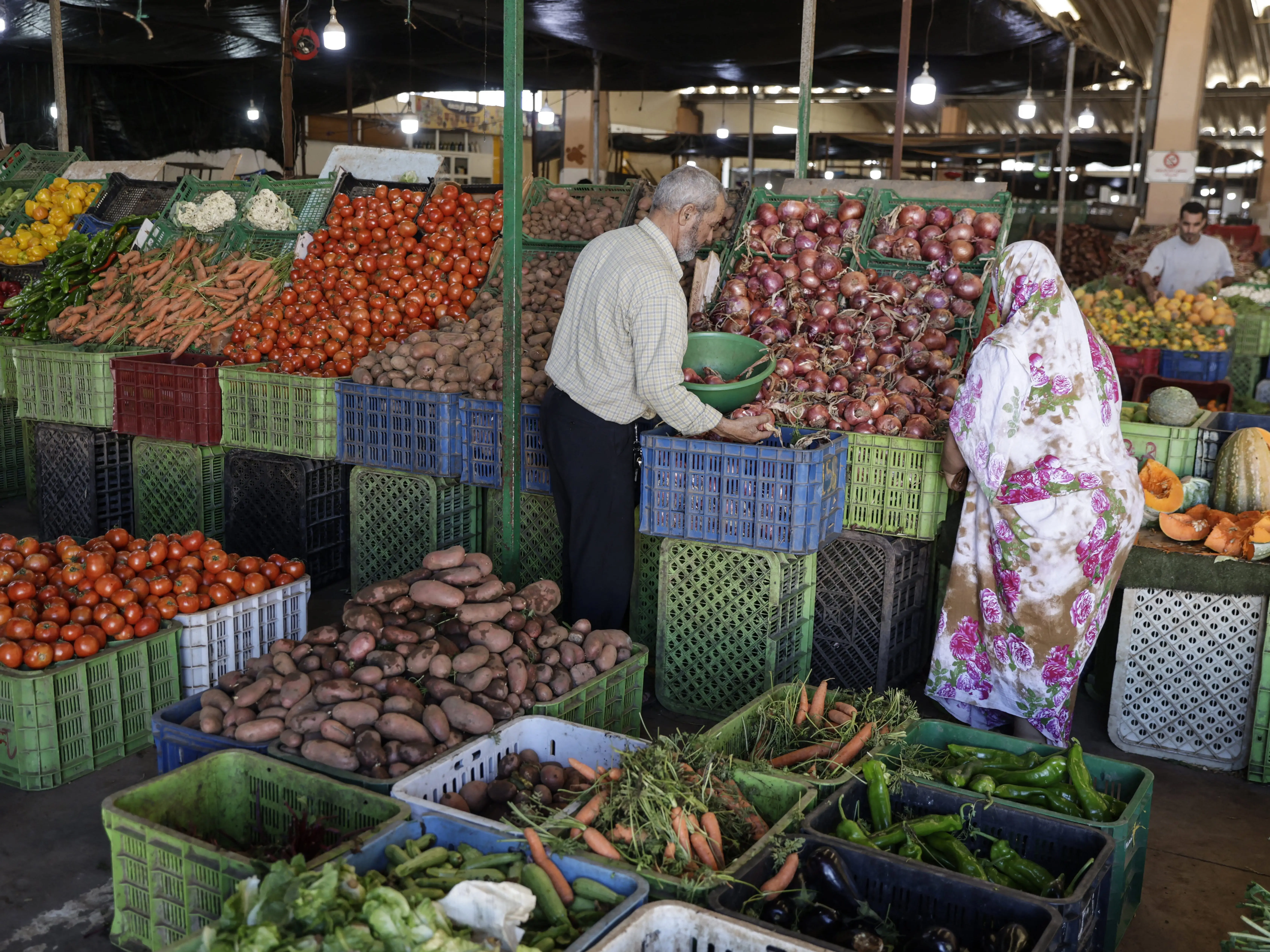 A man and a woman shopping for fruits and vegetables at a market.