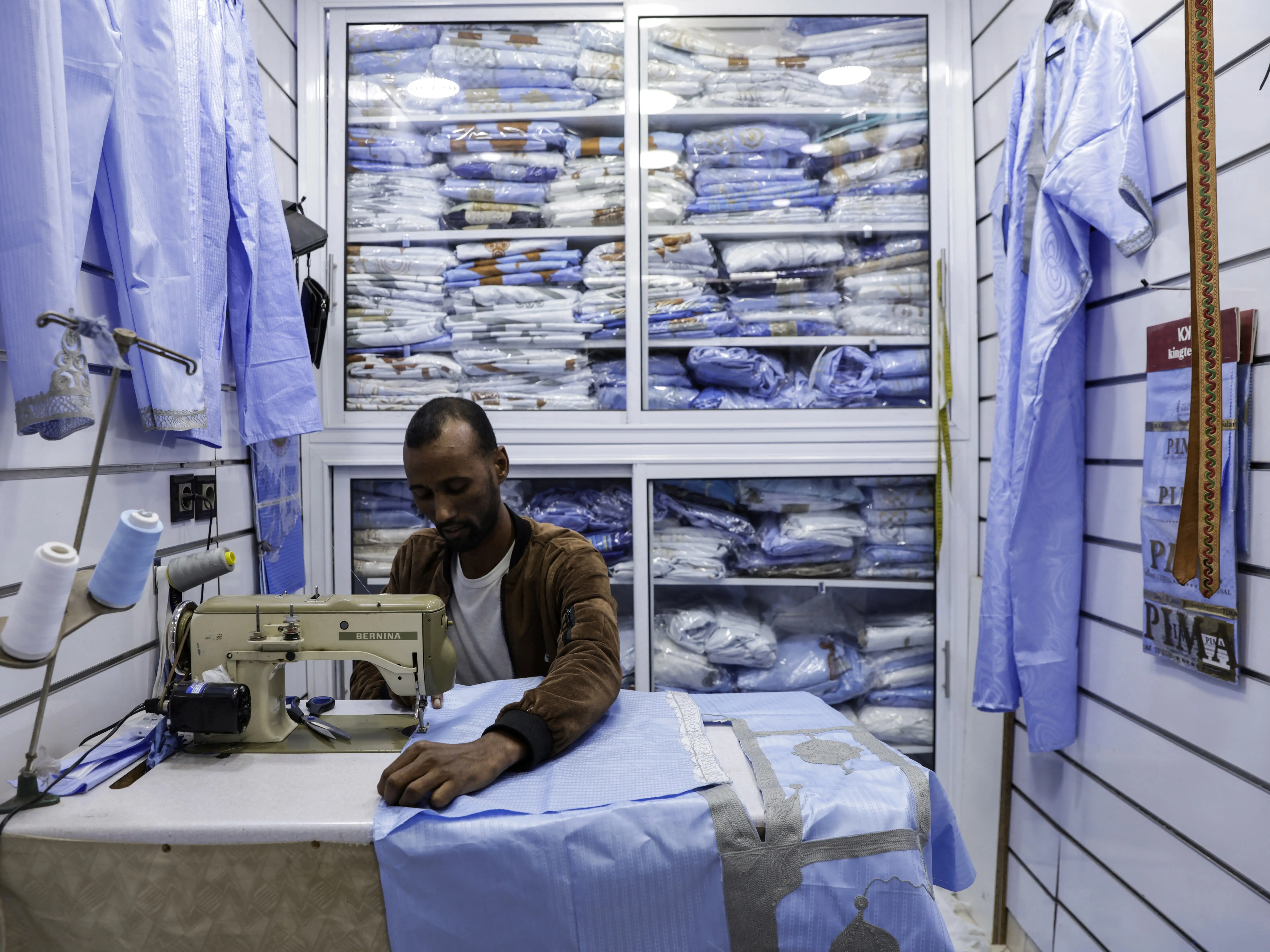 A man works on a garment with a sewing machine.